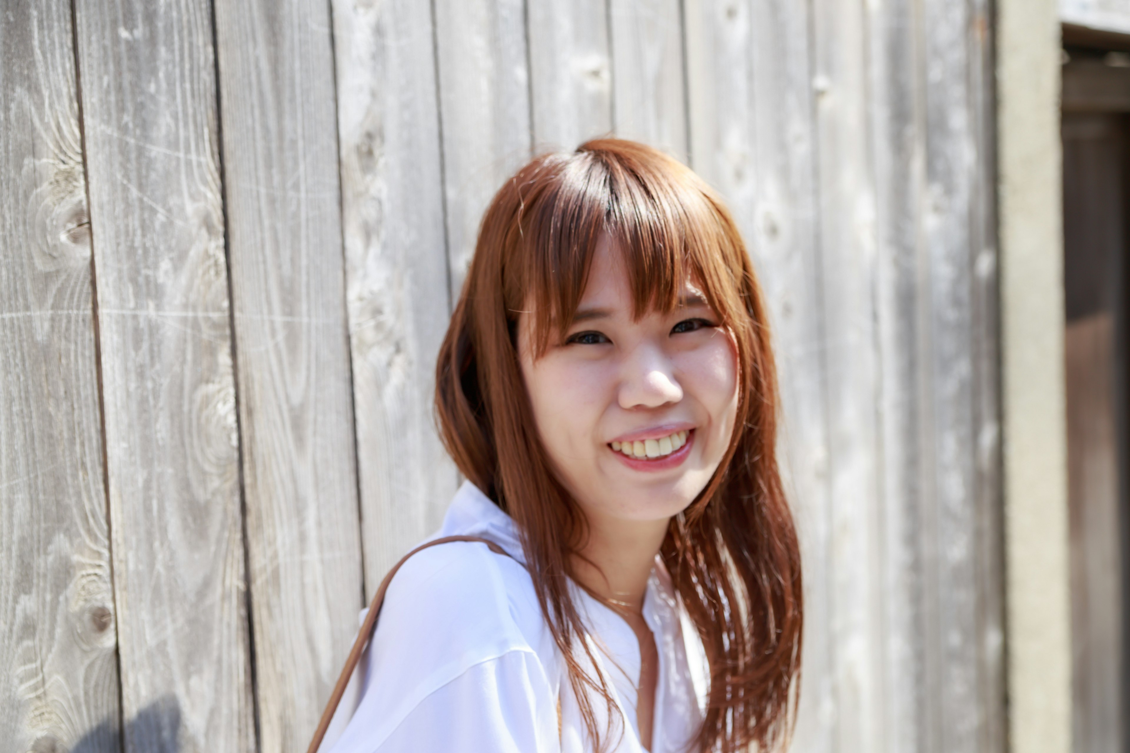 Une jeune femme souriante devant un mur en bois