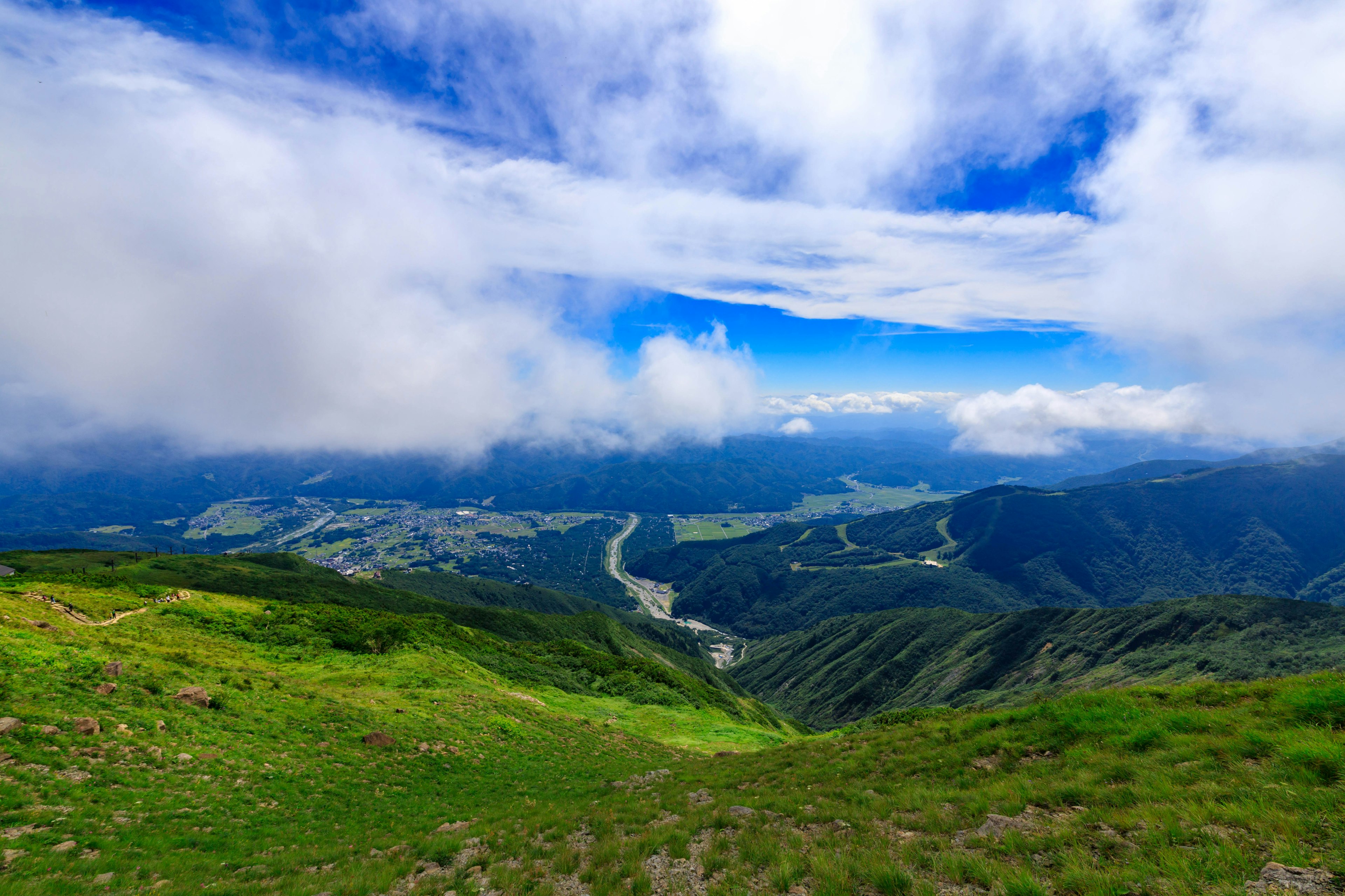 Pemandangan pegunungan dengan langit biru dan awan padang rumput hijau dan lembah