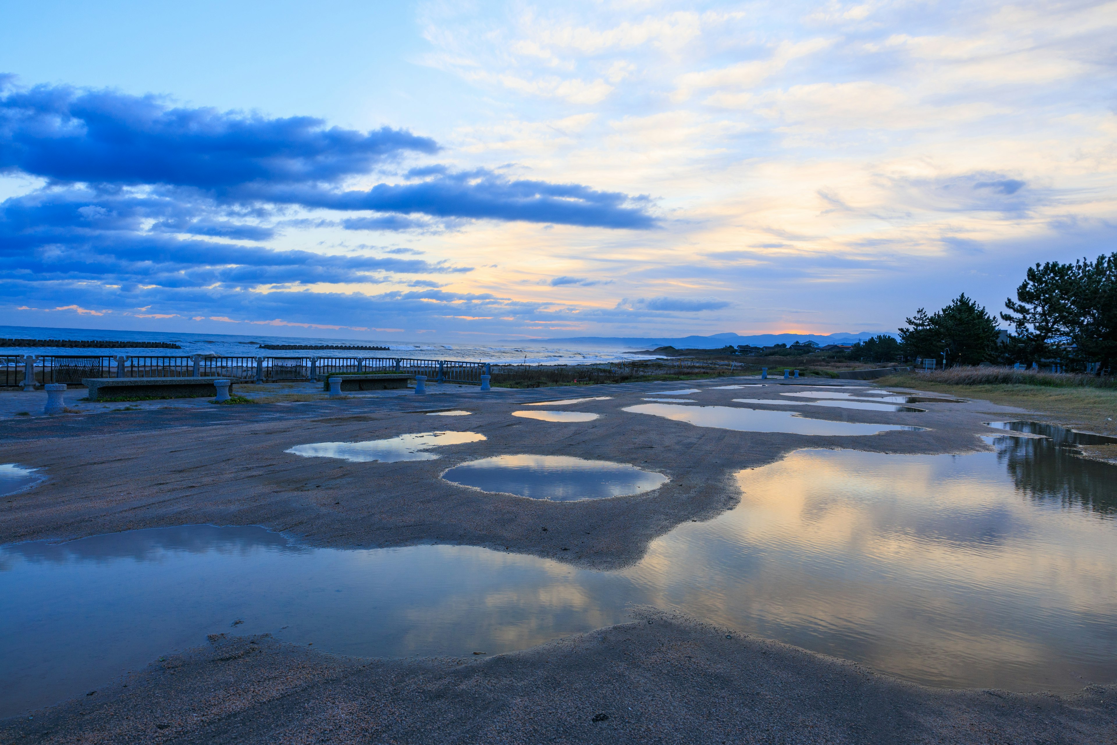 青い空と雲の下に水たまりが広がる海岸の風景