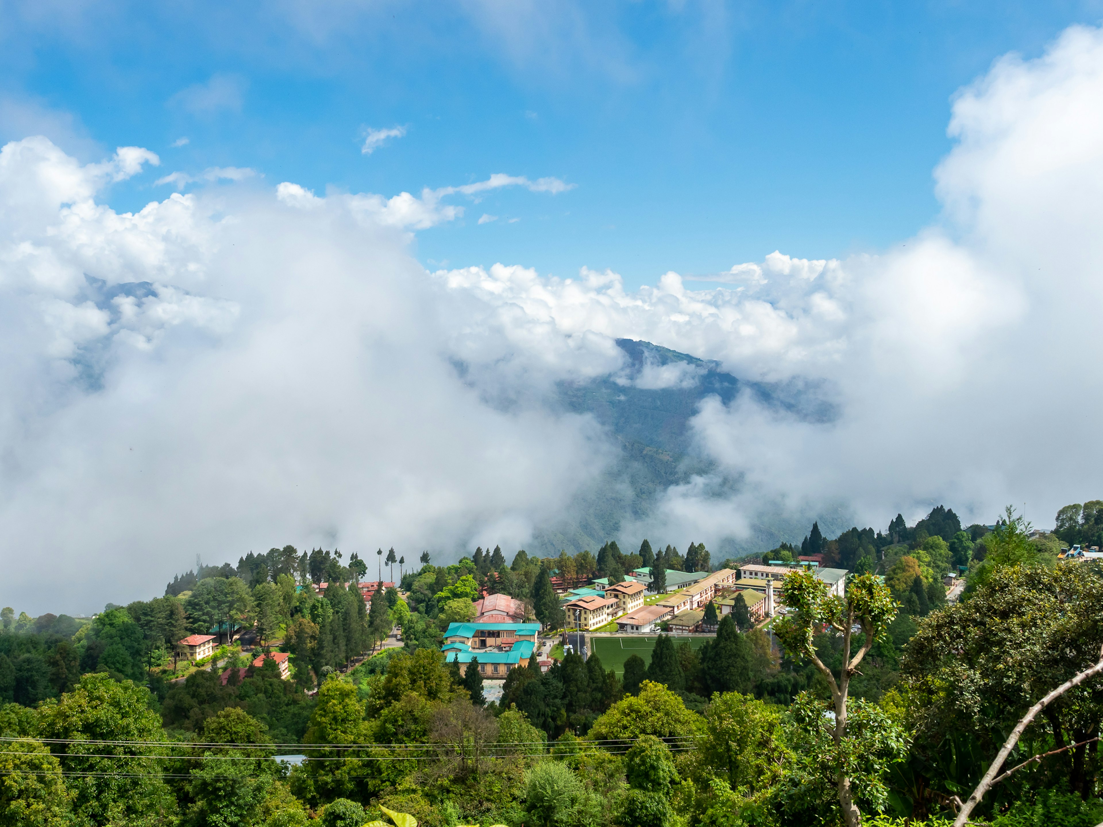 Malersicher Blick auf ein grünes Tal umgeben von Wolken und blauem Himmel