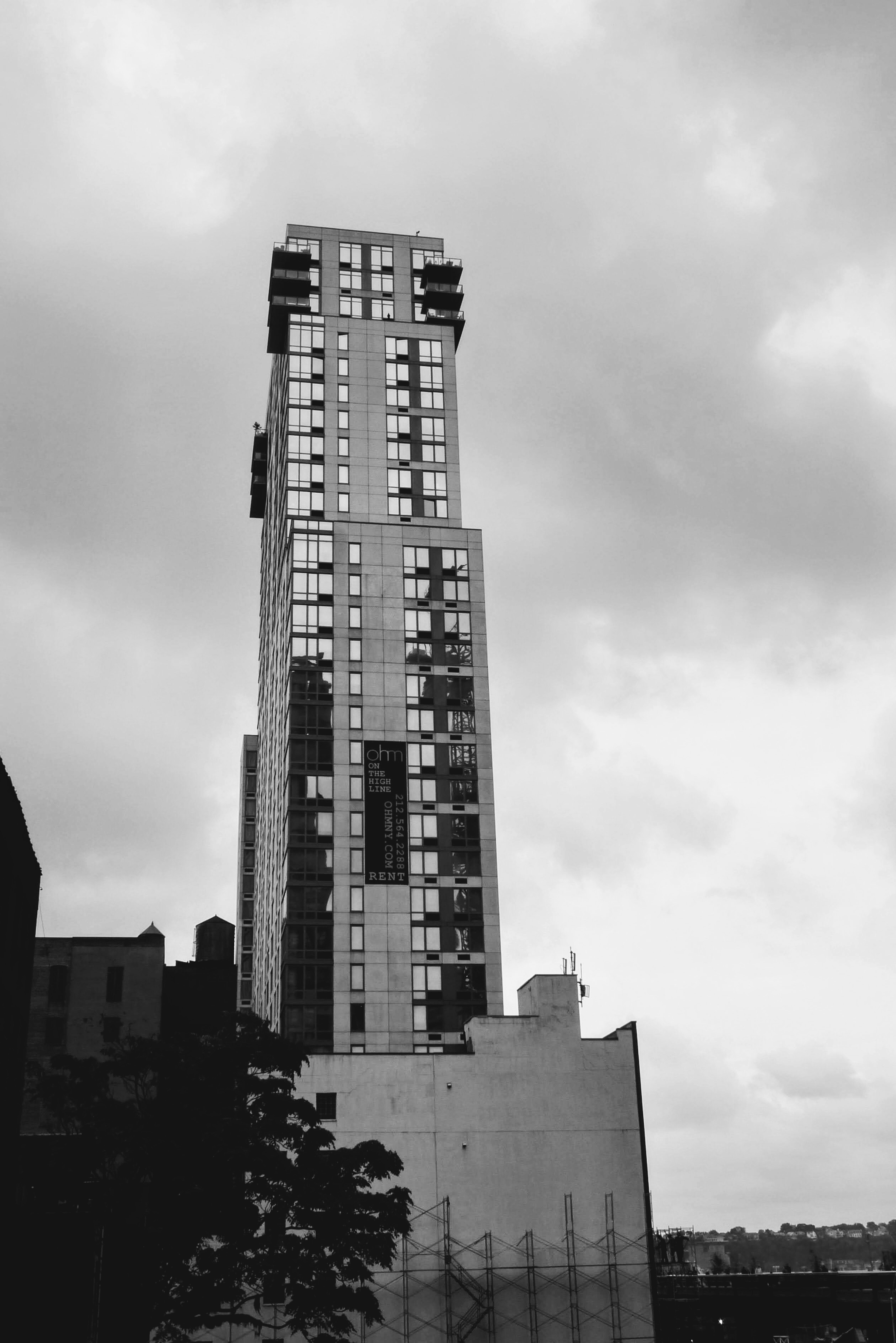 Black and white image of a tall building with a cloudy sky