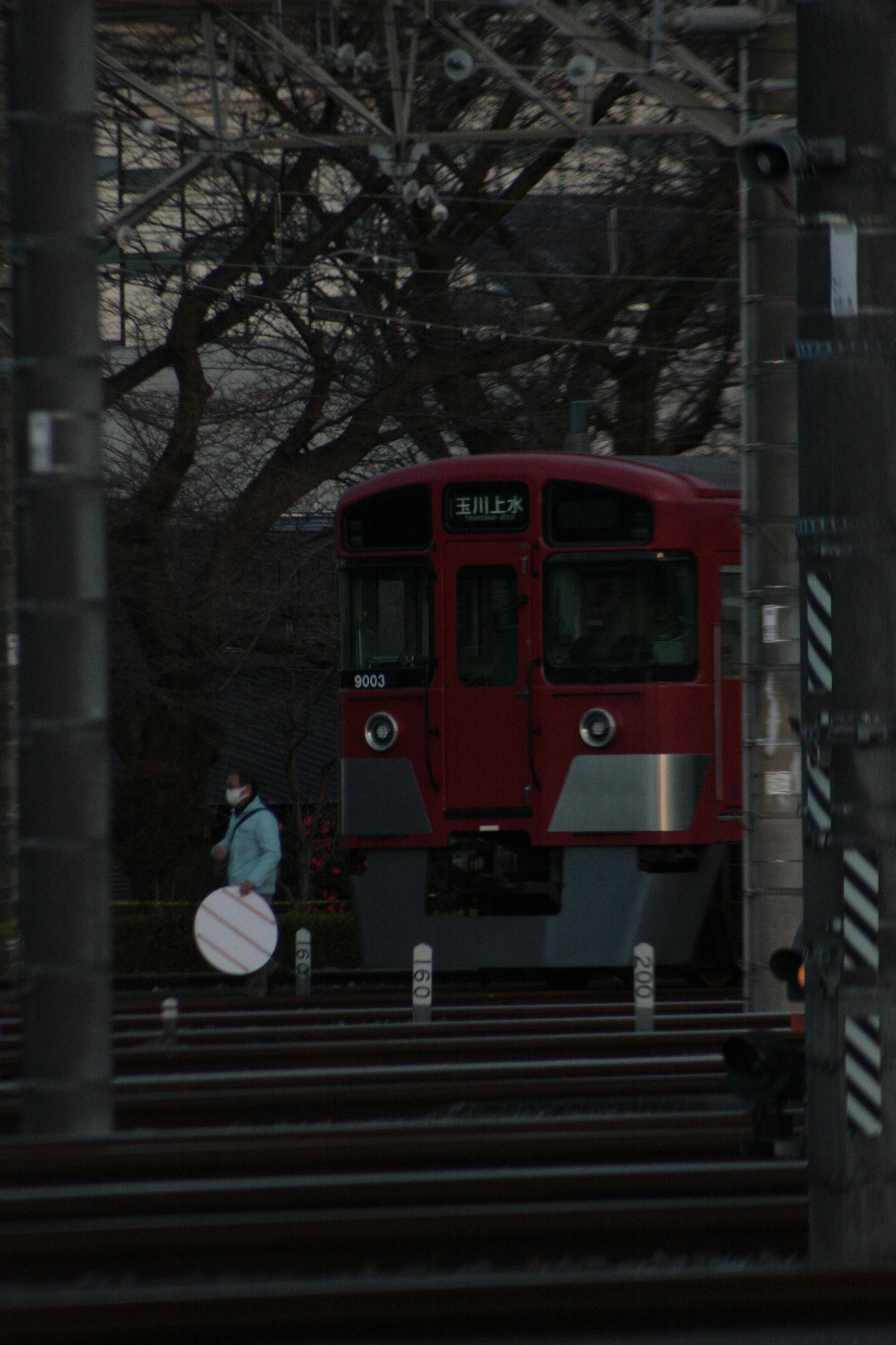 Red train with a silhouette of a person along the tracks