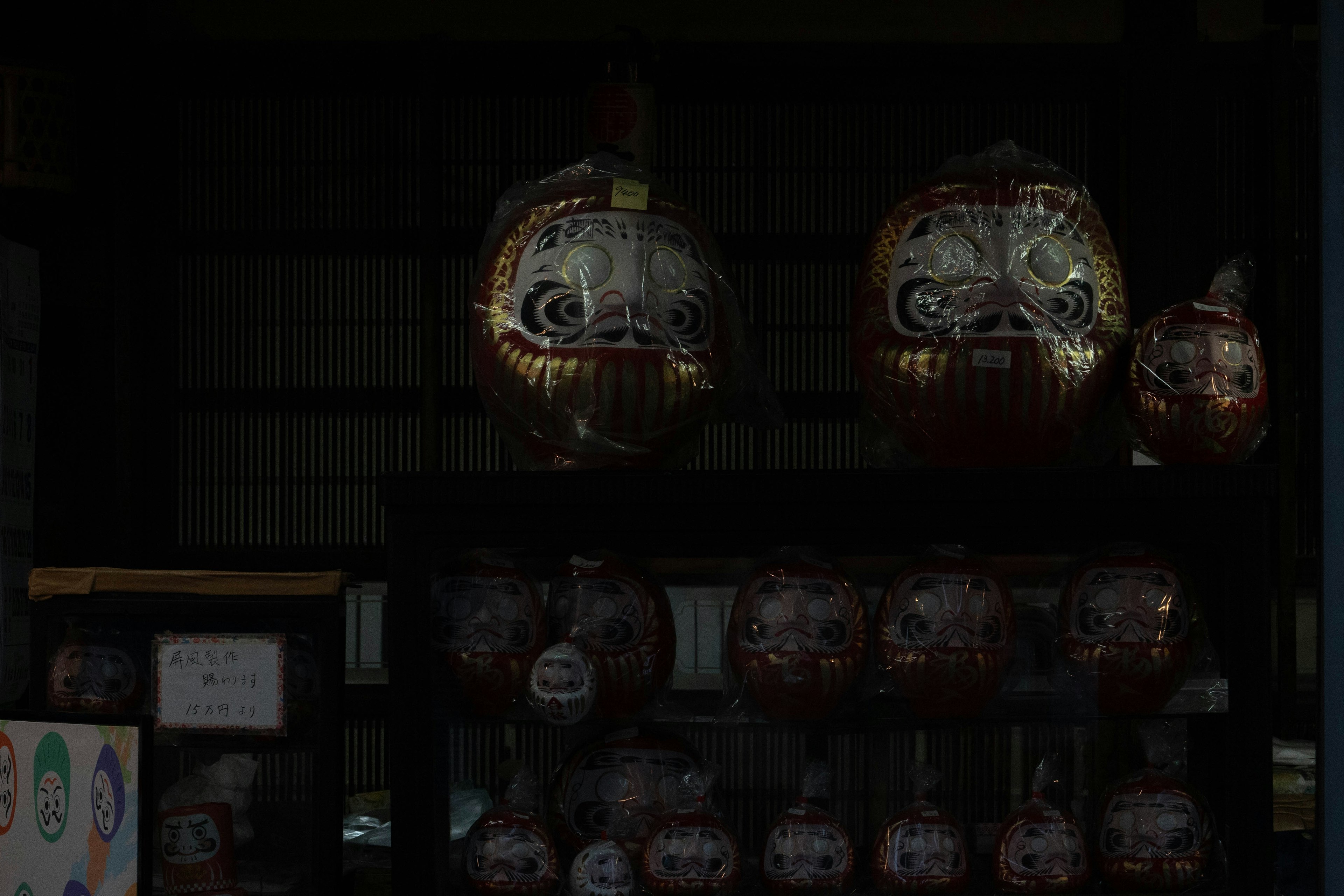 Muñecas daruma japonesas tradicionales exhibidas sobre un fondo oscuro