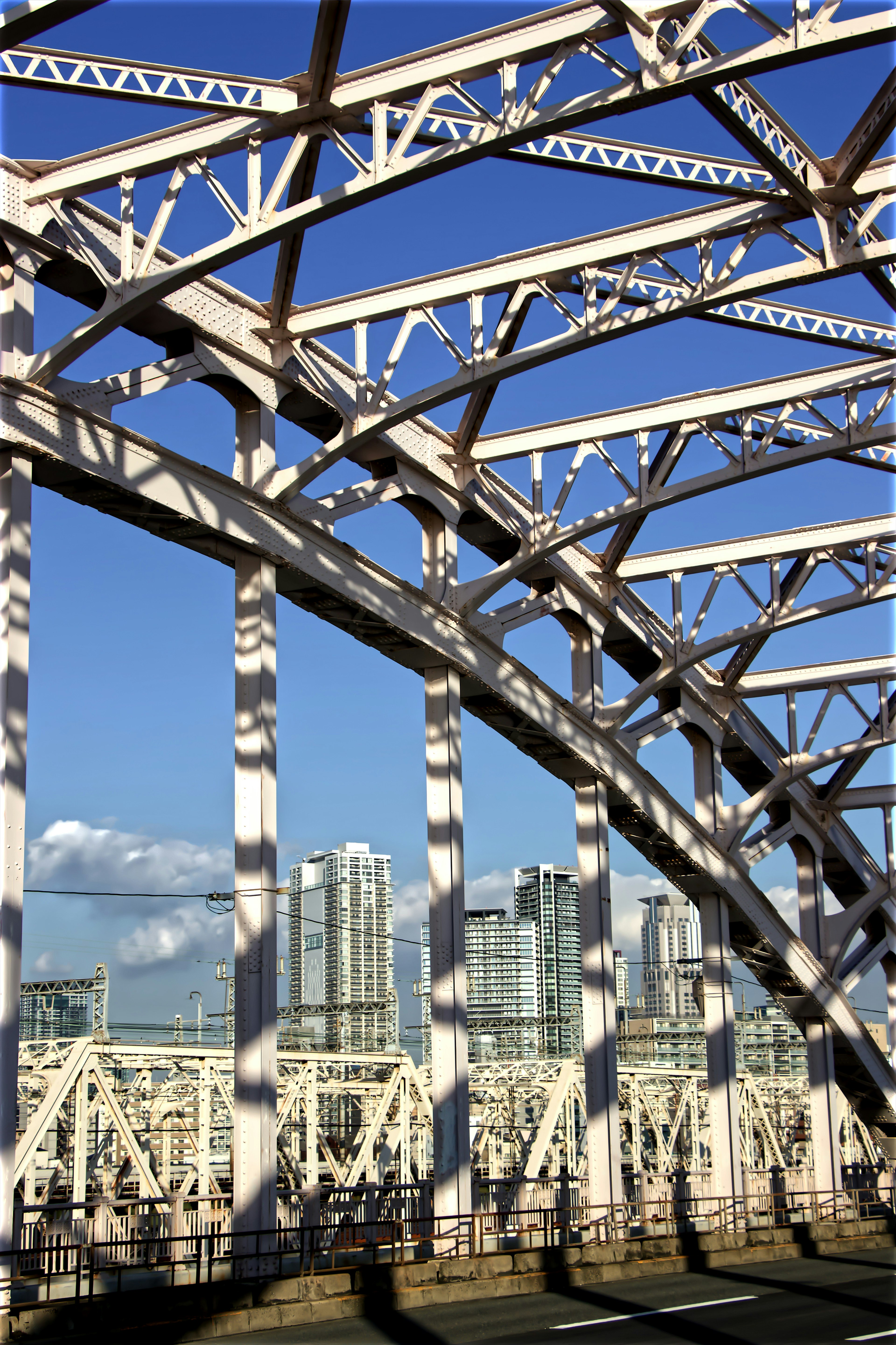 Structure de pont en acier blanc sous un ciel bleu avec ligne d'horizon urbaine