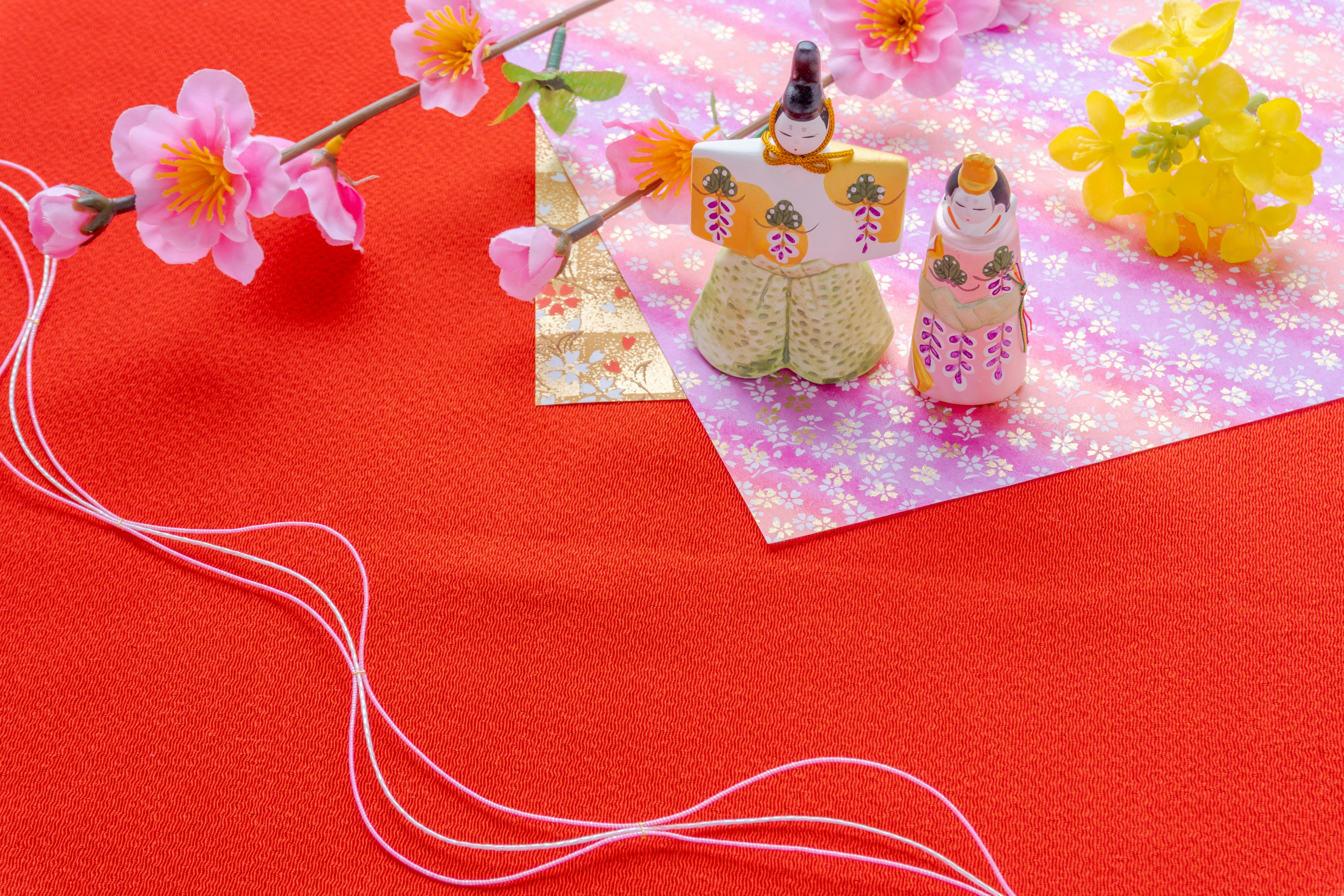 Muñecas Hinamatsuri con decoraciones florales sobre un fondo rojo