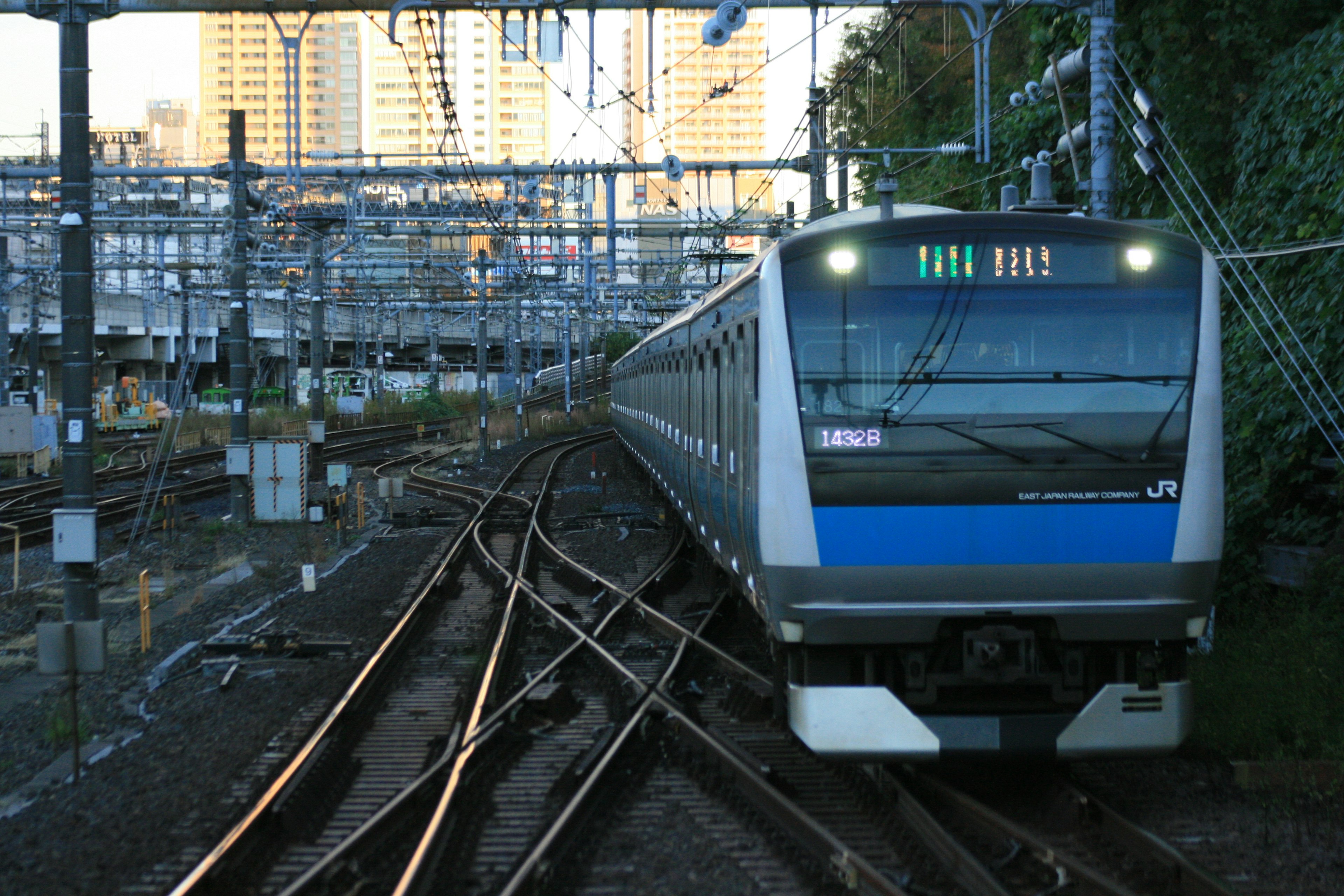 Tren azul navegando por múltiples vías en un entorno urbano