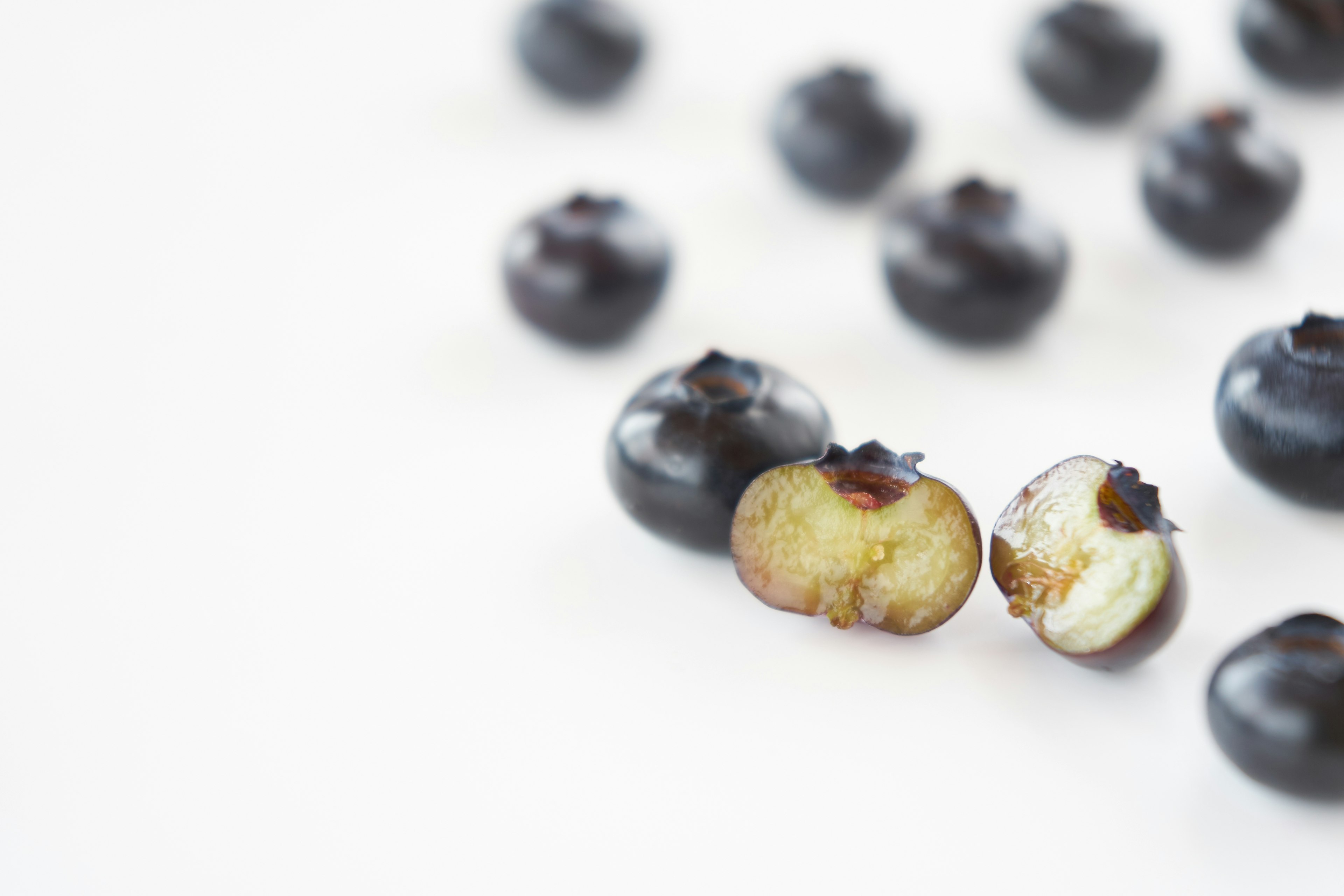 Black blueberries and a sliced blueberry showing its interior