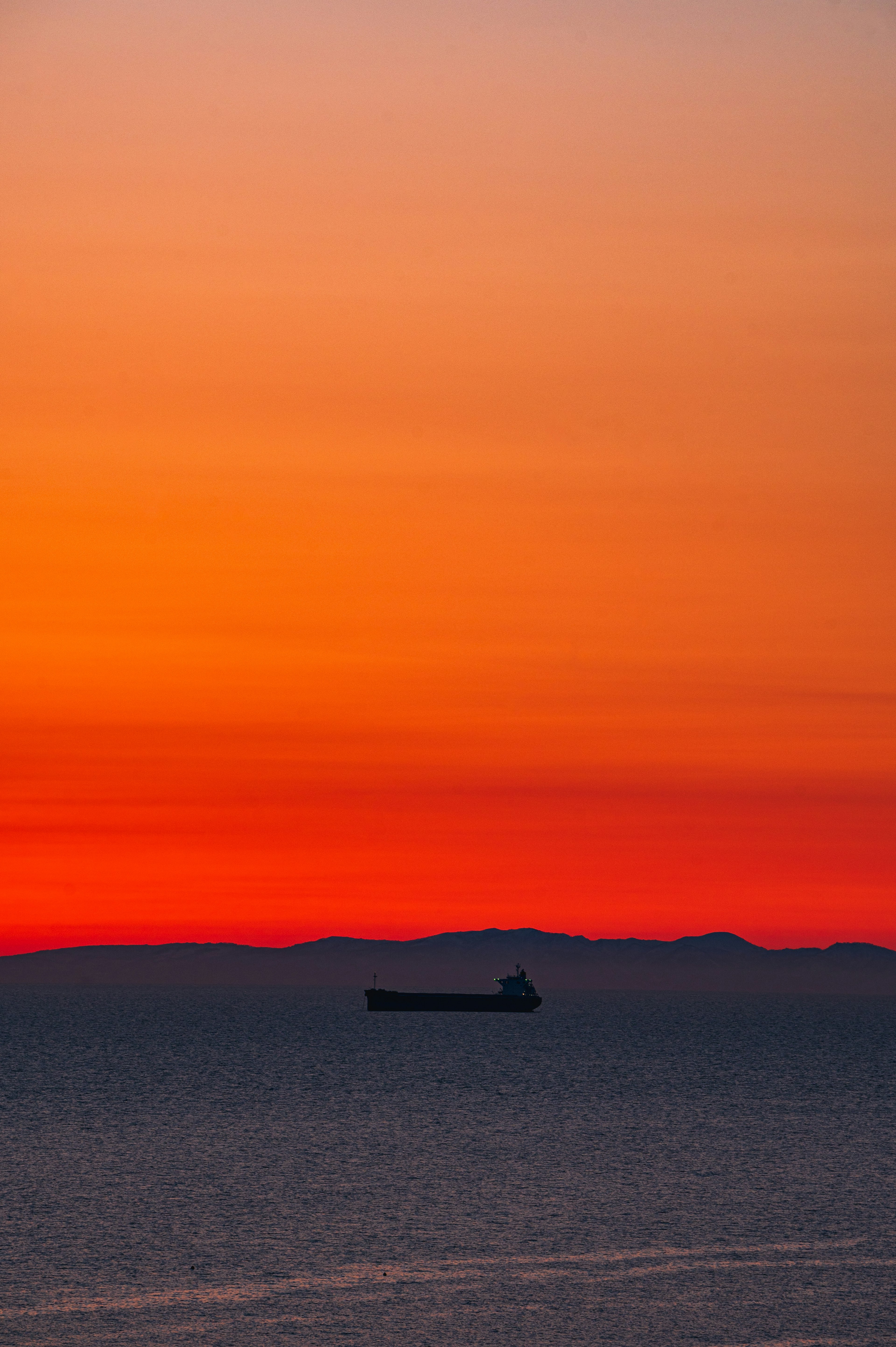 夕焼けの海に浮かぶ船のシルエット