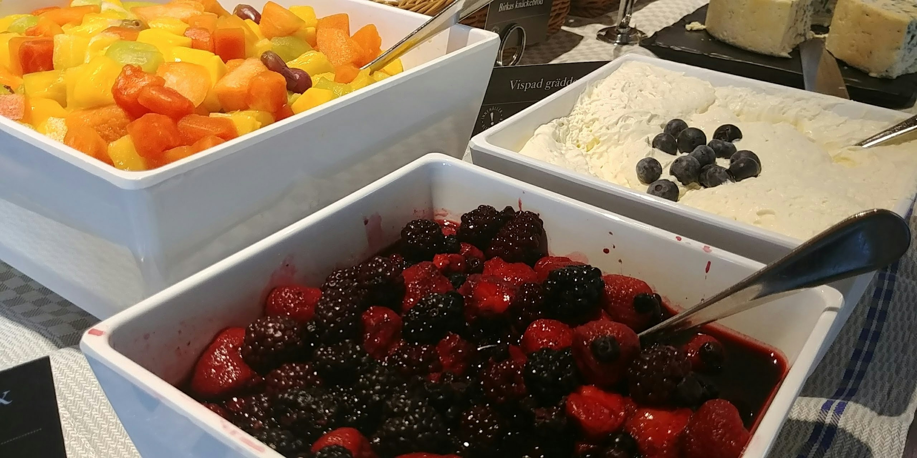 A buffet style dessert table featuring assorted fruits and cream