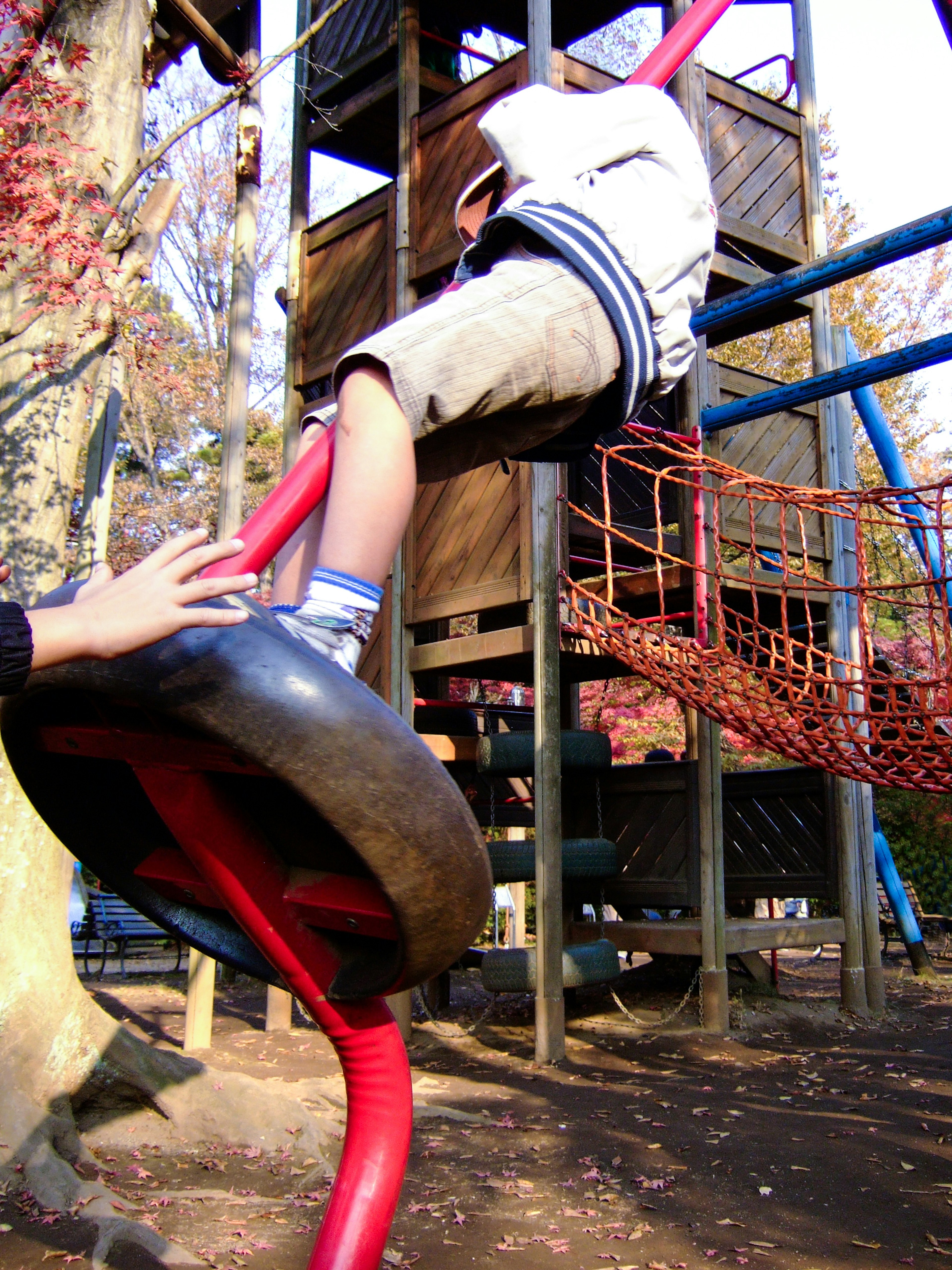 Child playing on playground equipment gripping a red pipe