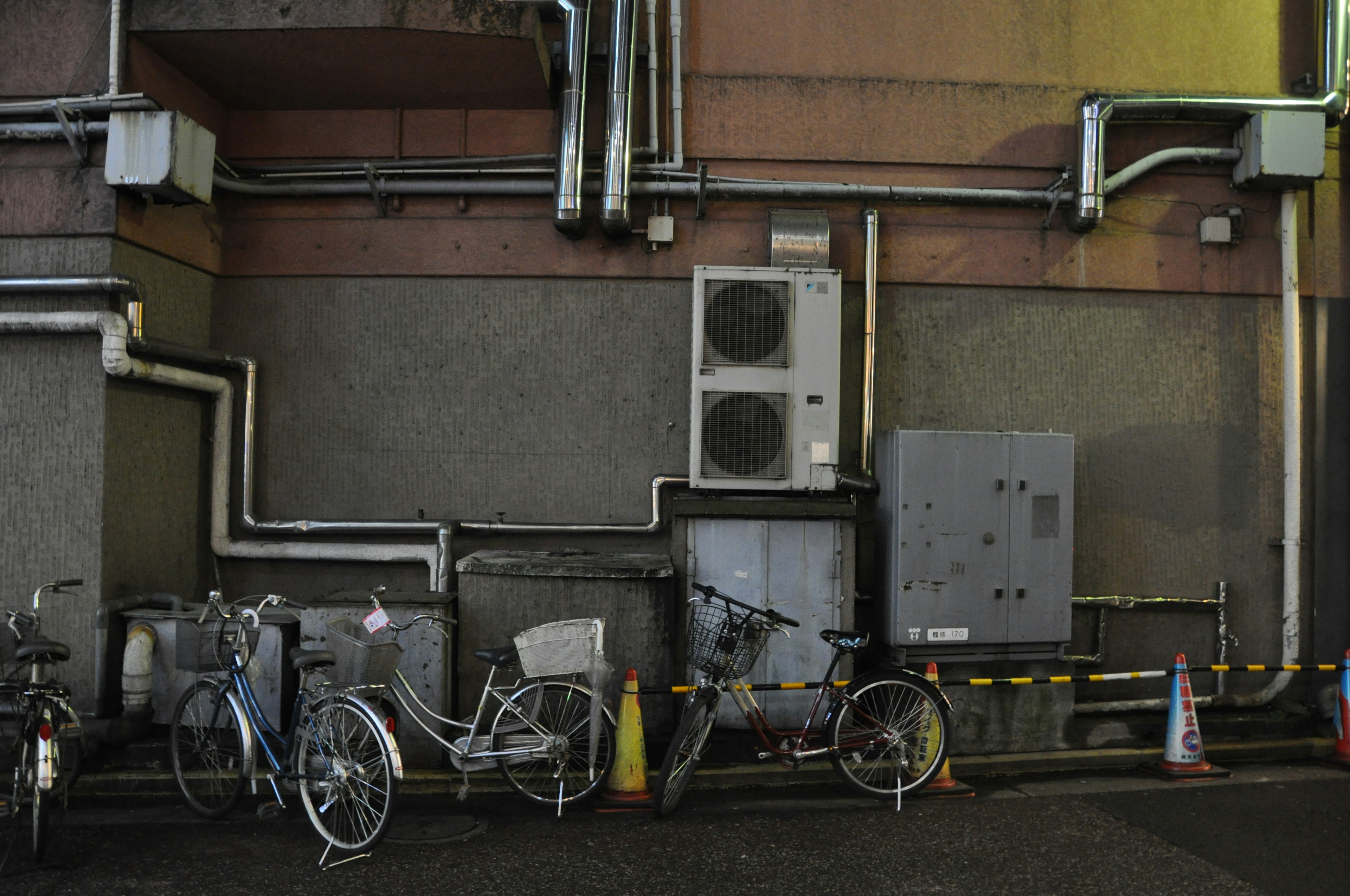 Bicicletas alineadas contra una pared con tuberías y características industriales visibles