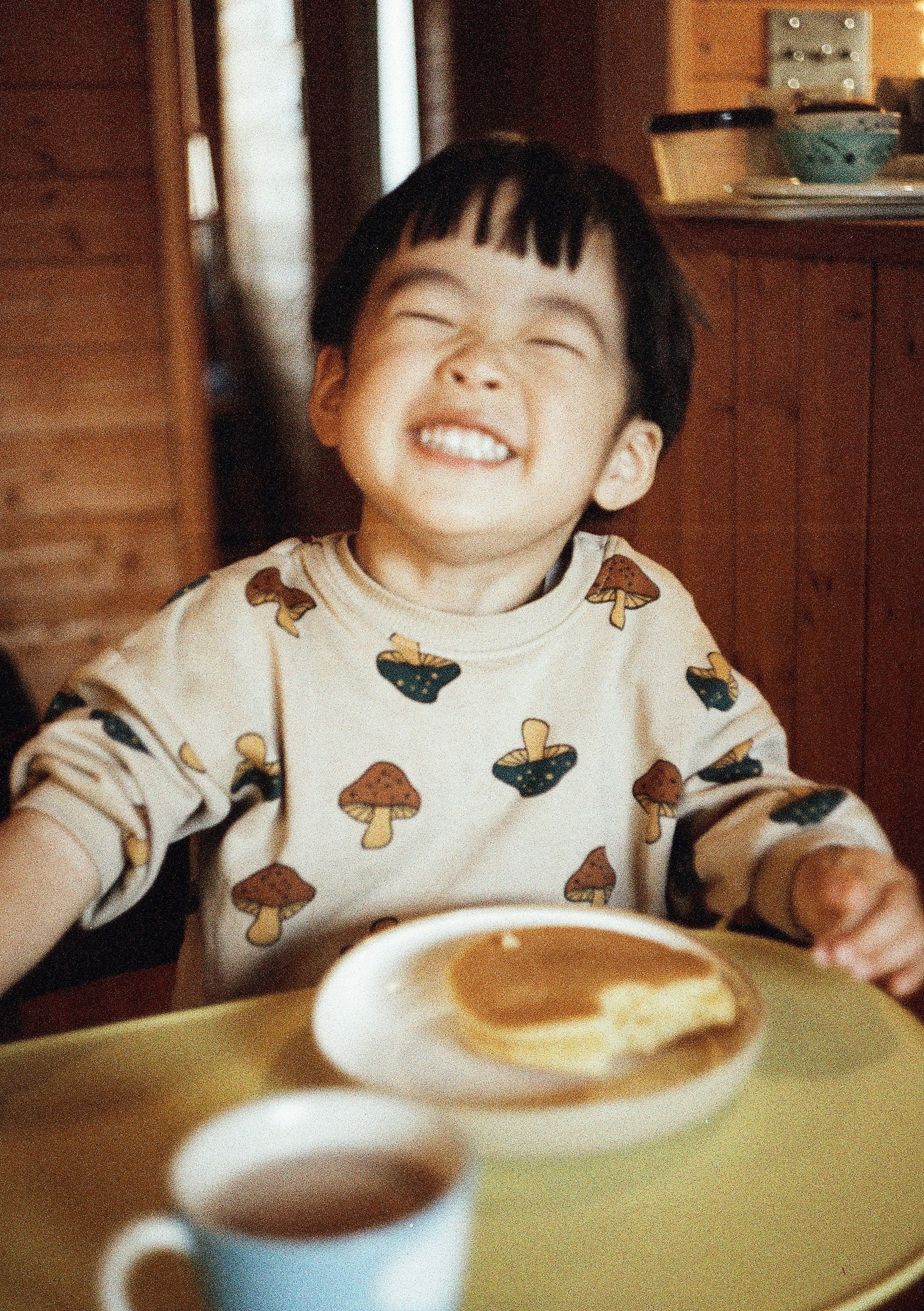 Anak tersenyum menikmati pancake di meja yang nyaman