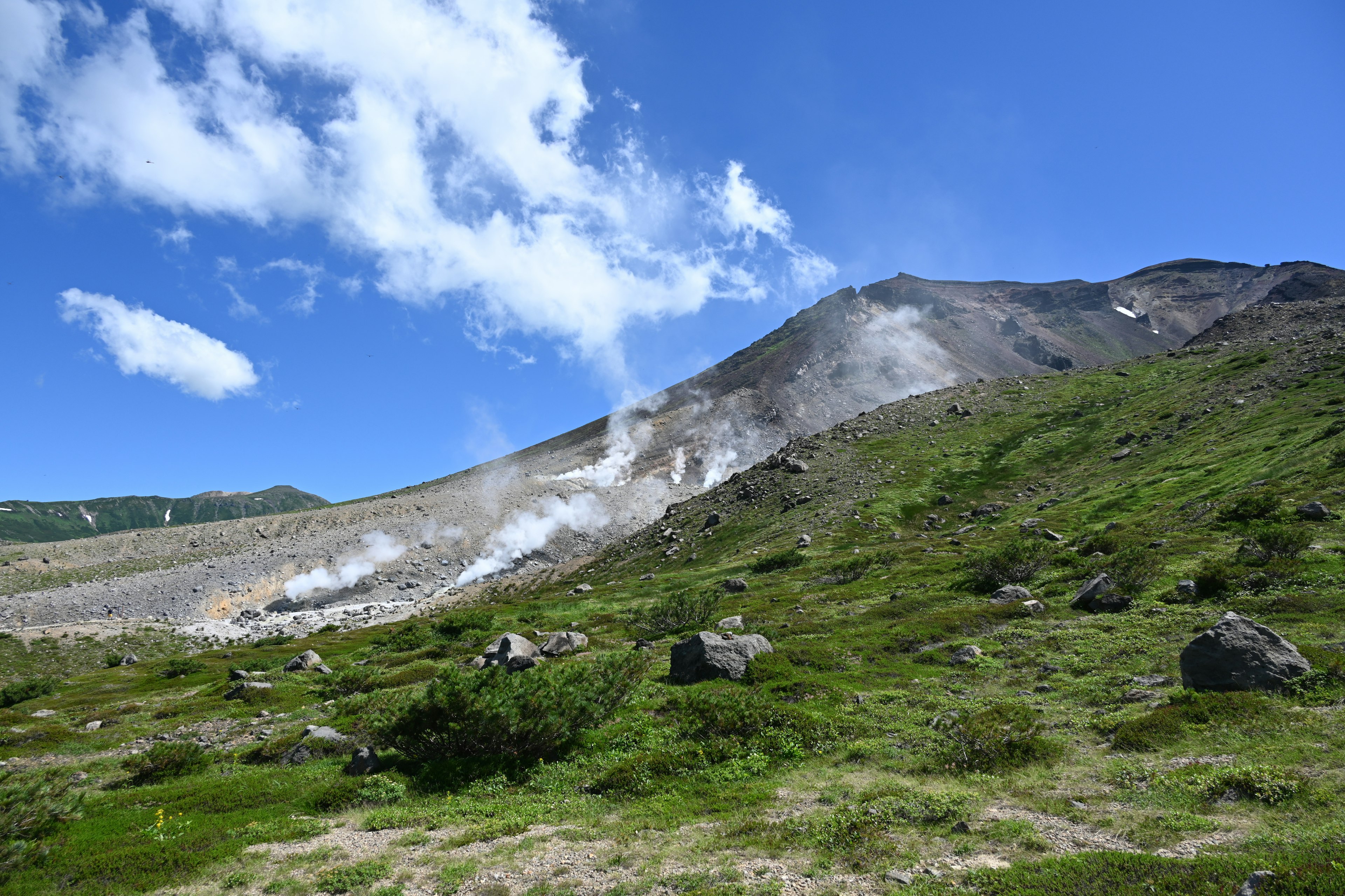 Pente de volcan actif avec vapeur et ciel bleu