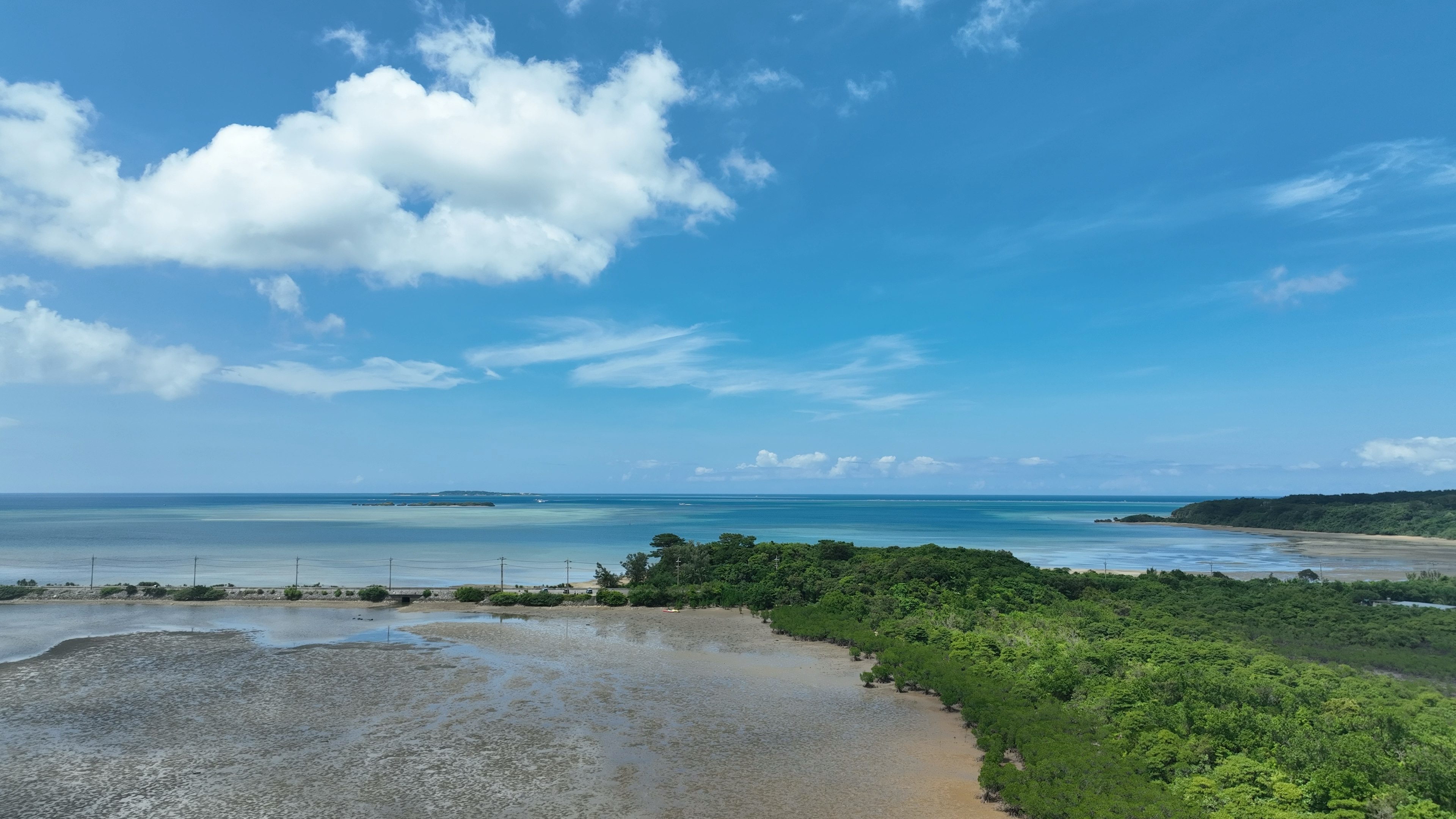 Coastal landscape with blue sky and white clouds green vegetation and calm sea colors