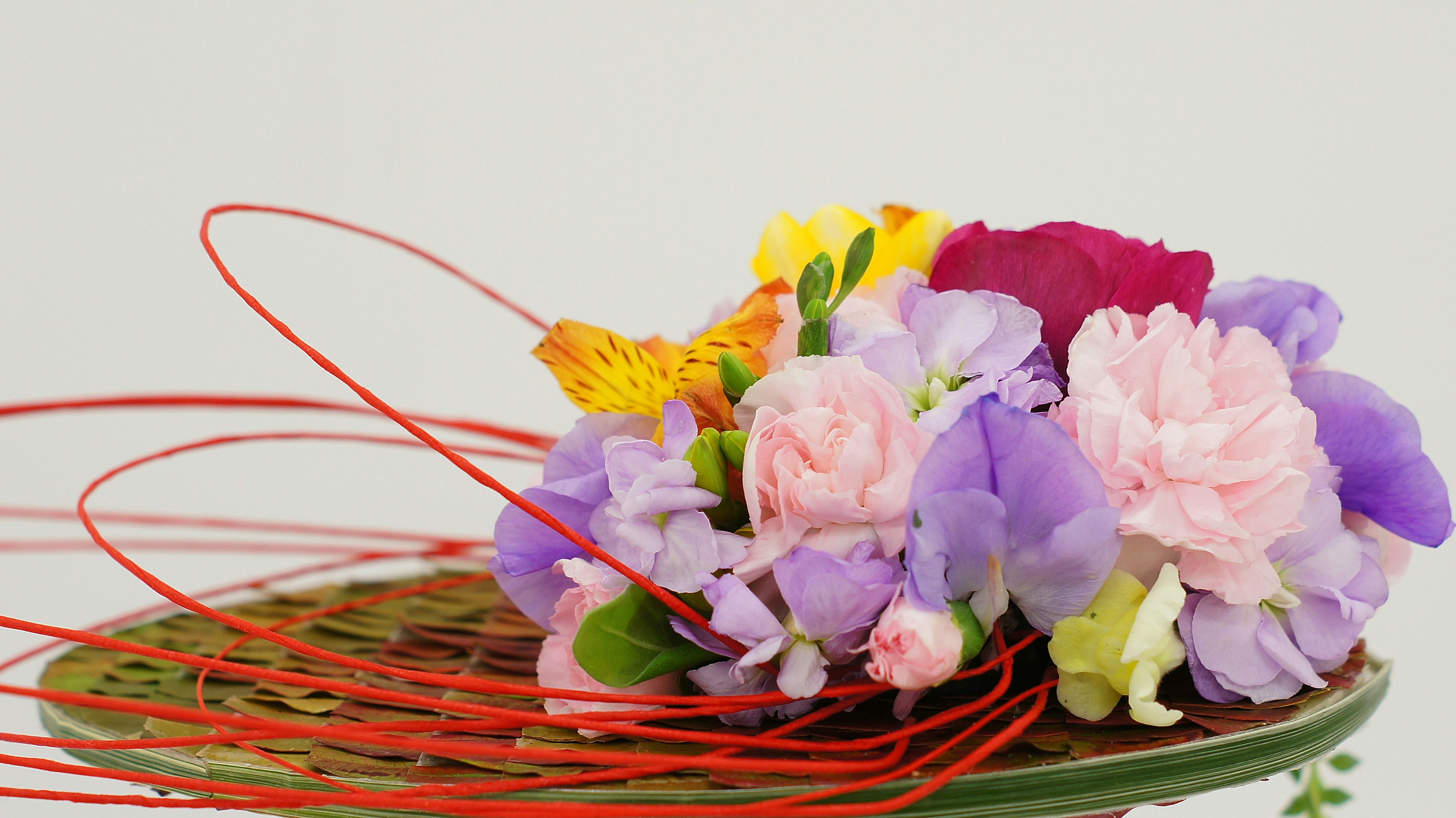 Hermoso arreglo floral con flores coloridas y acentos de alambre rojo