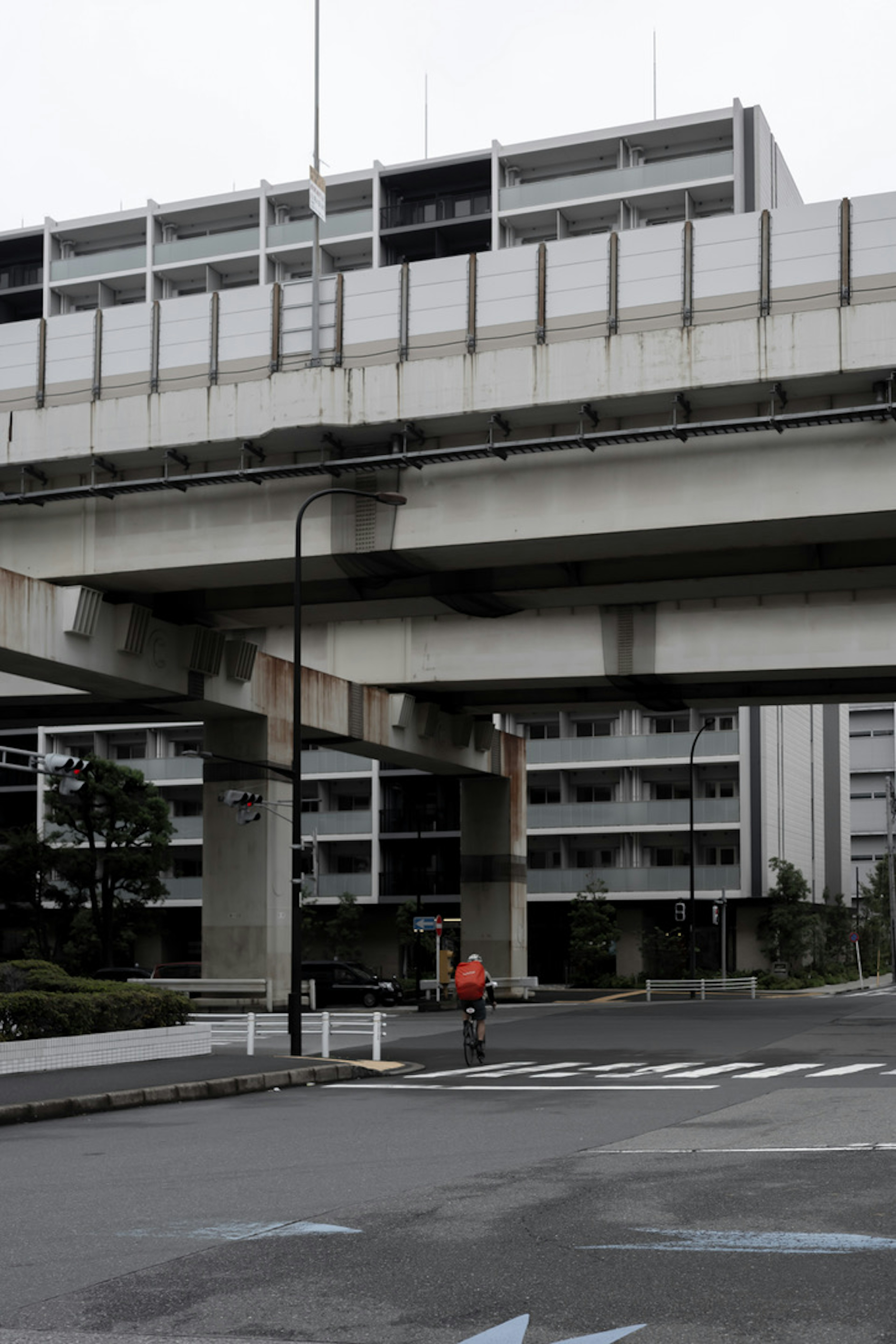 Paisaje urbano con una carretera elevada y edificios residenciales con un ciclista pasando