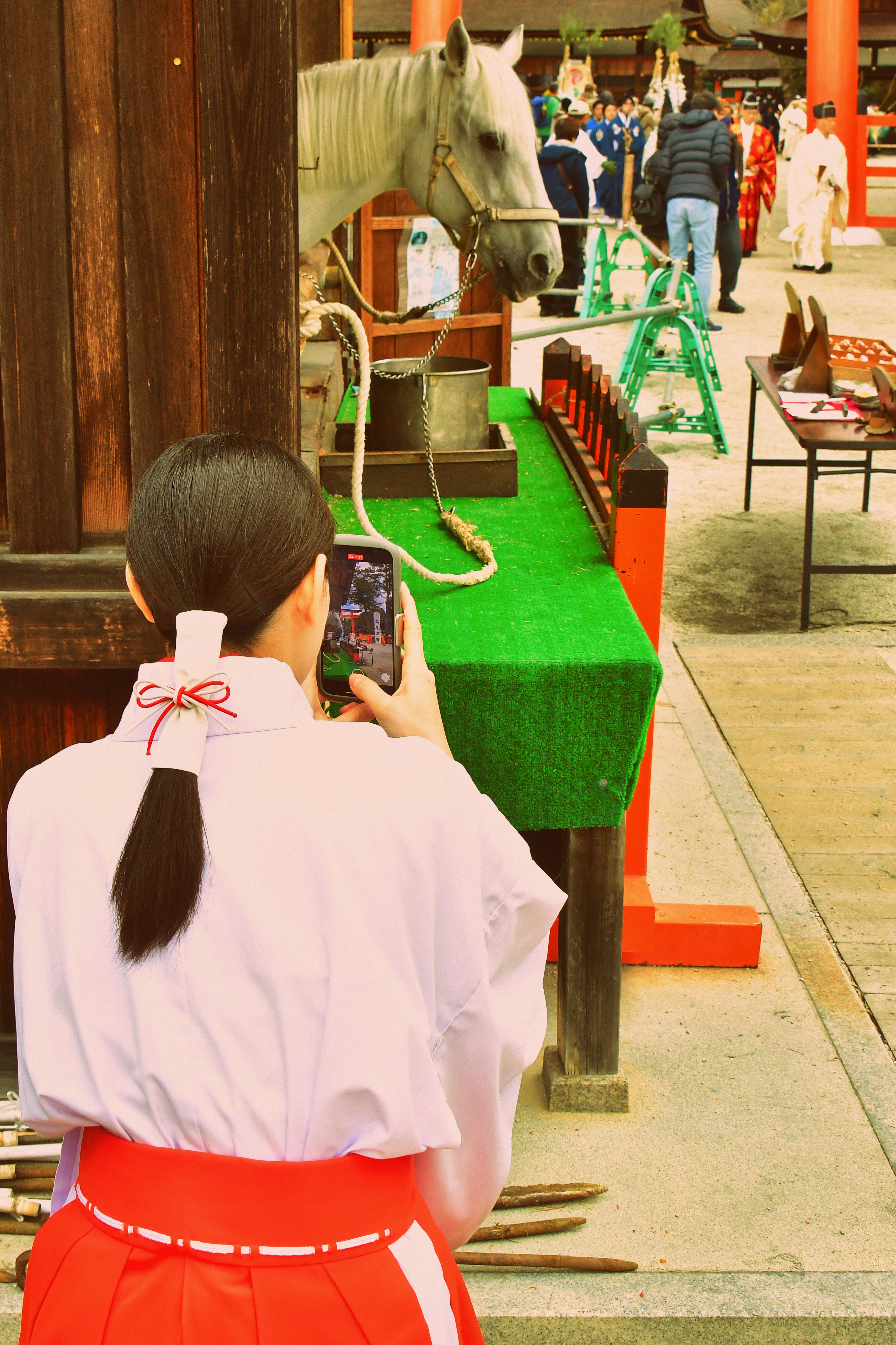 伝統的な服装を着た女性が馬を撮影している神社の風景