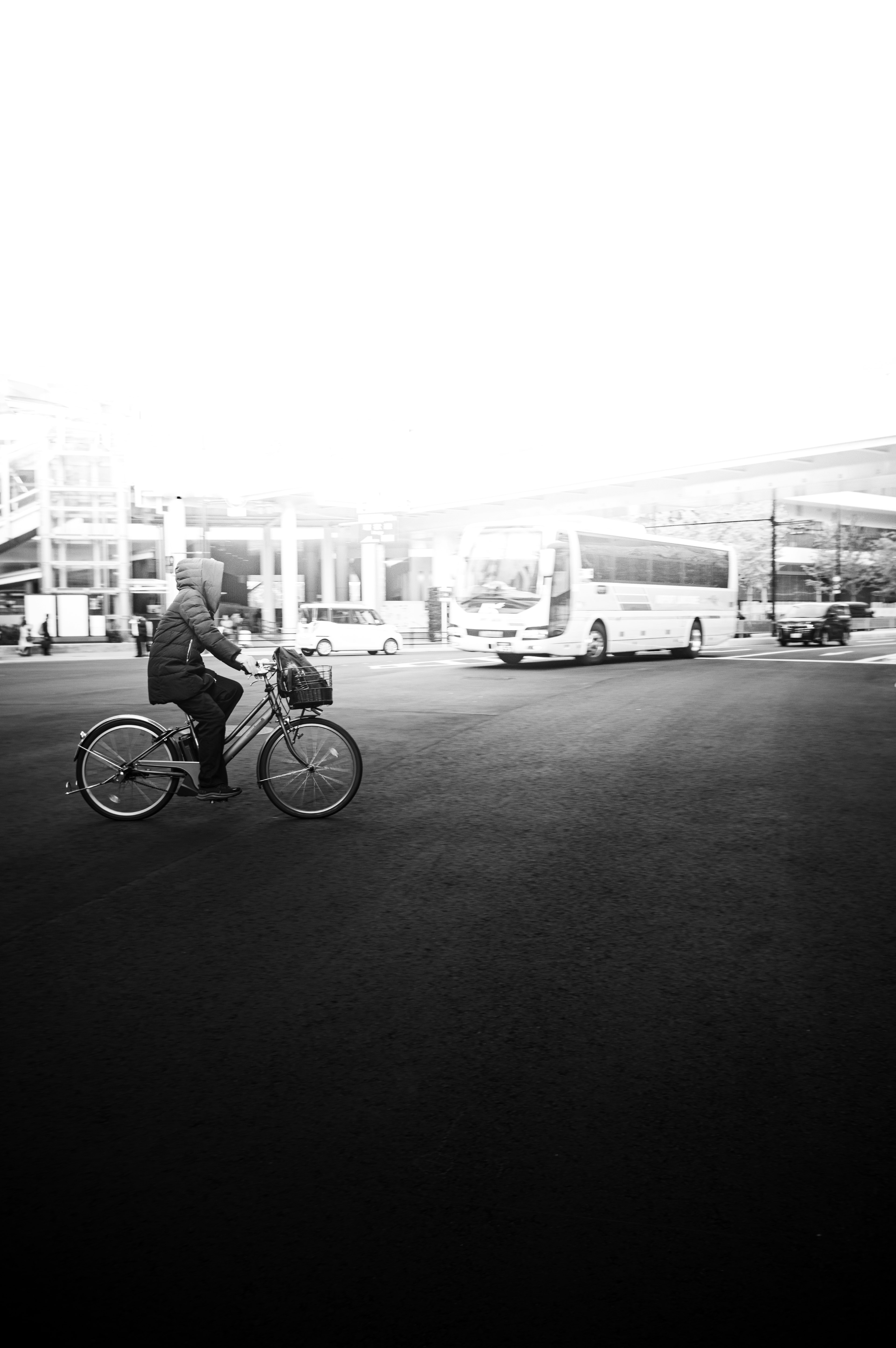 Hombre montando una bicicleta en un paisaje urbano en blanco y negro con autobuses