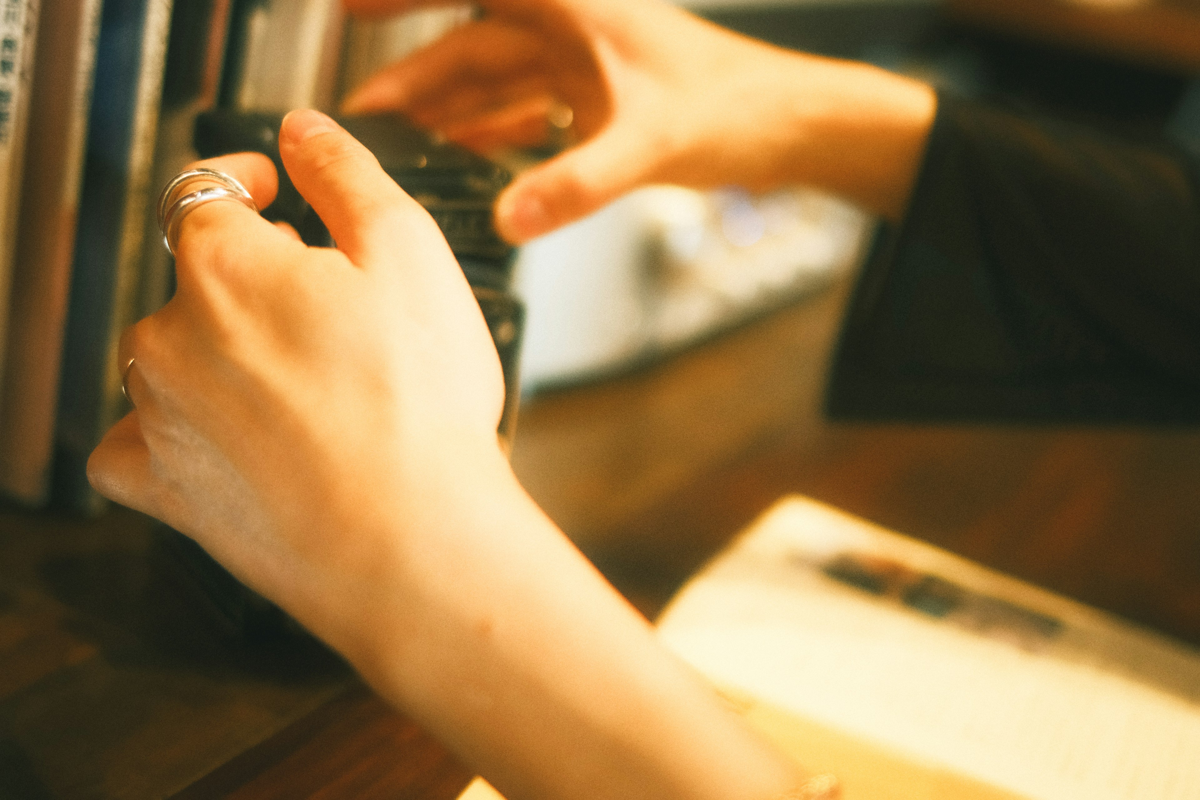 Hands holding a camera with books in the background