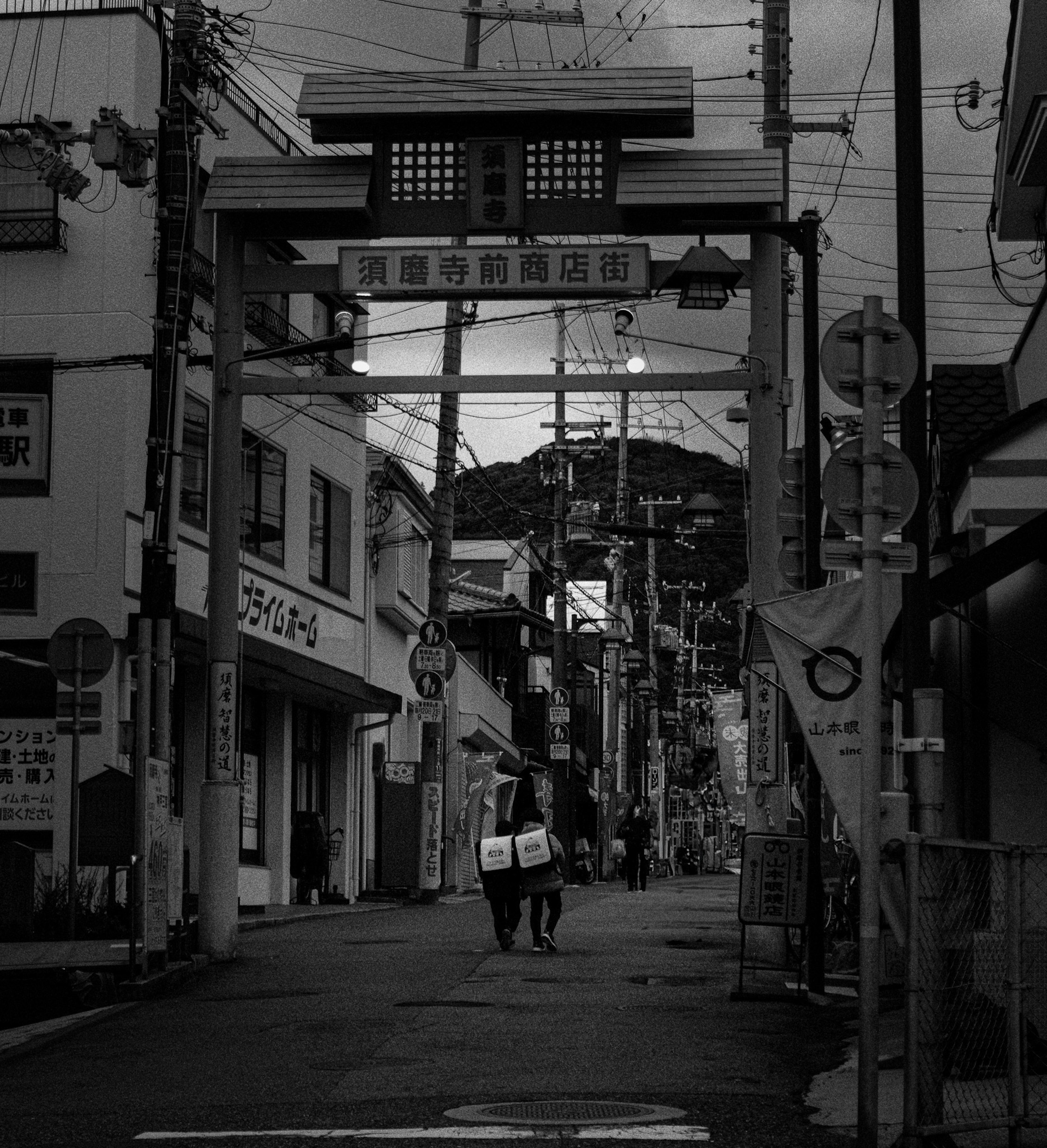 Torii gate in a black and white street scene with people walking