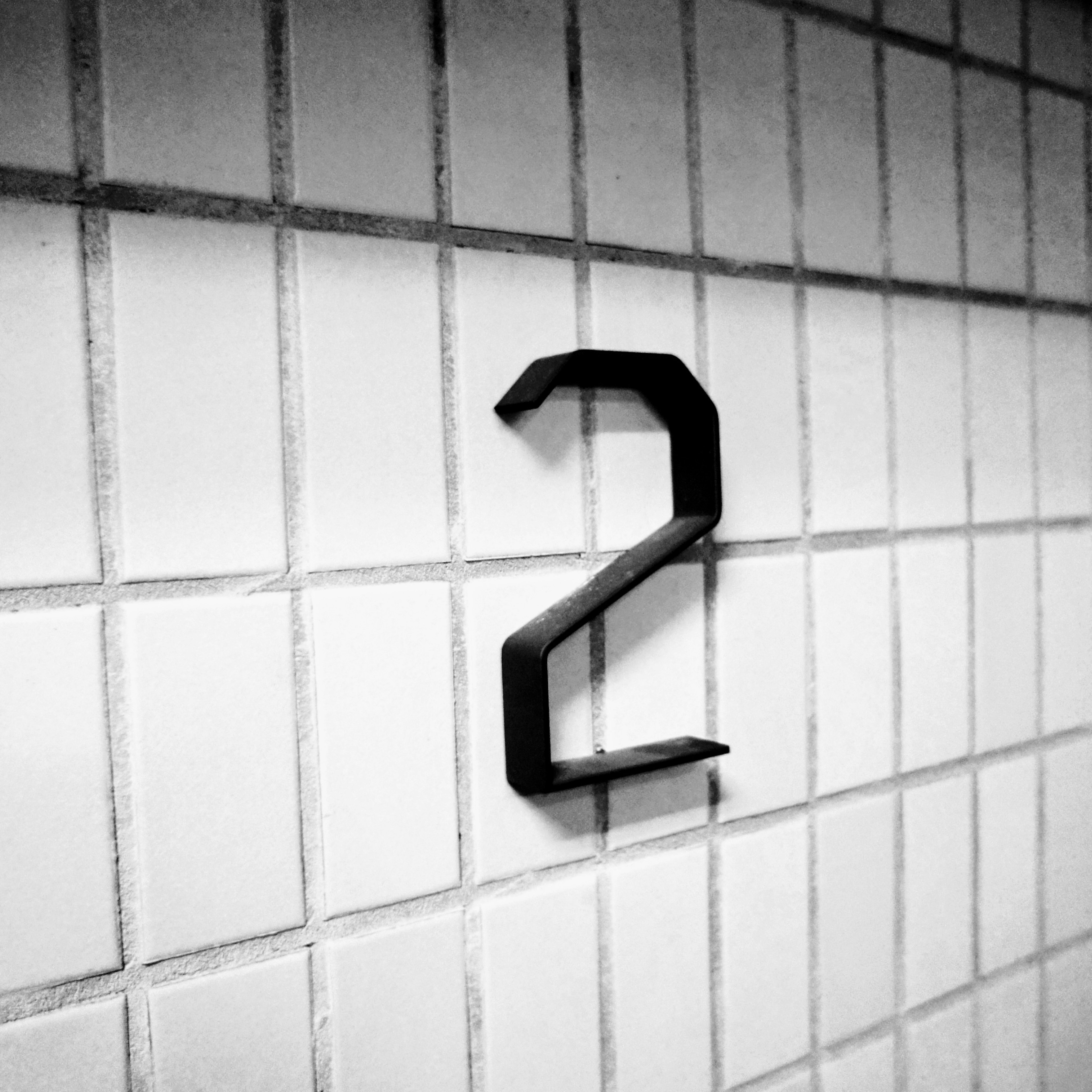 Black number 2 mounted on a white tiled wall