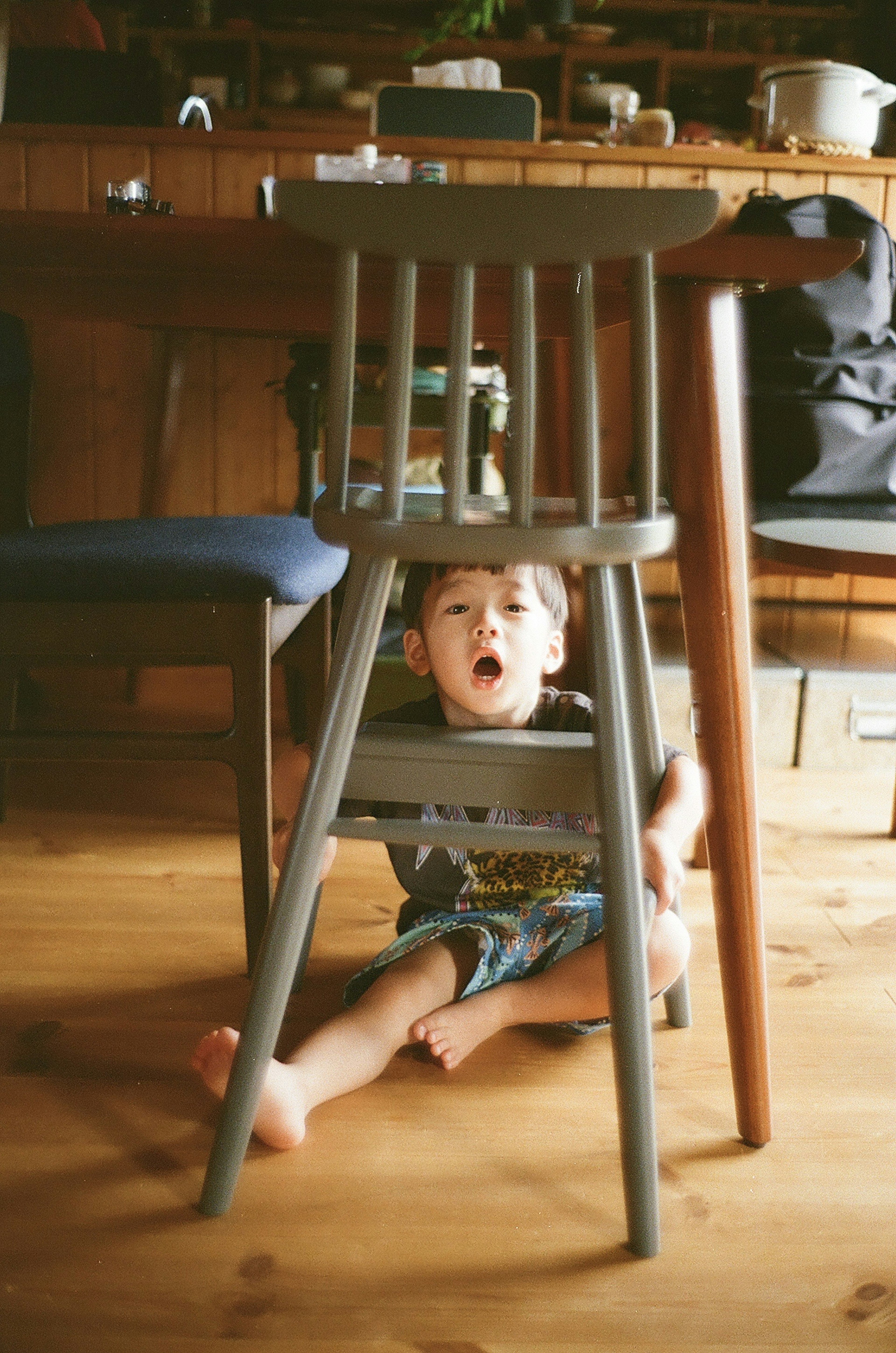 Child hiding under a chair in a cozy interior