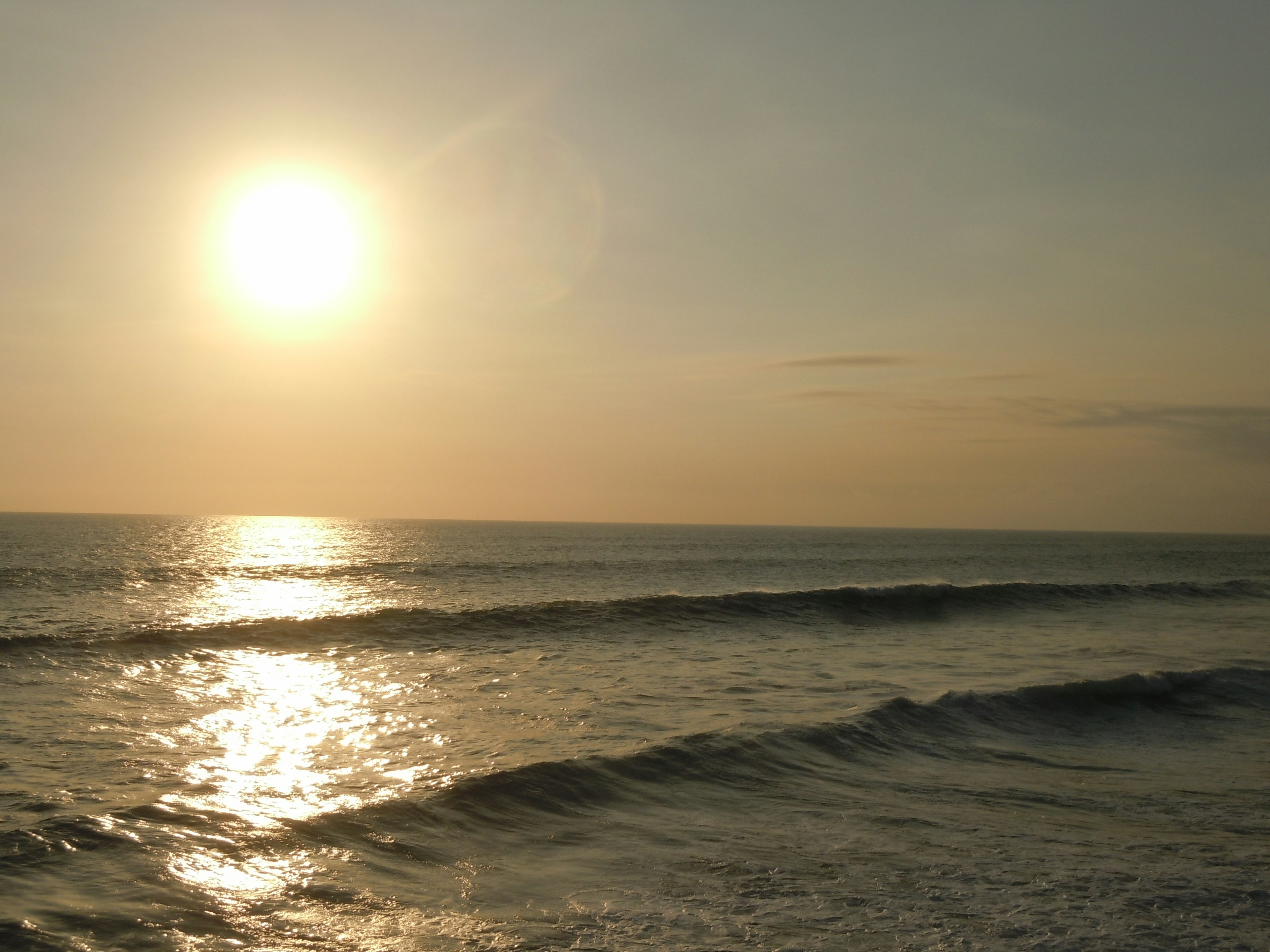 A beautiful landscape of the sunset over the ocean with waves and shimmering water