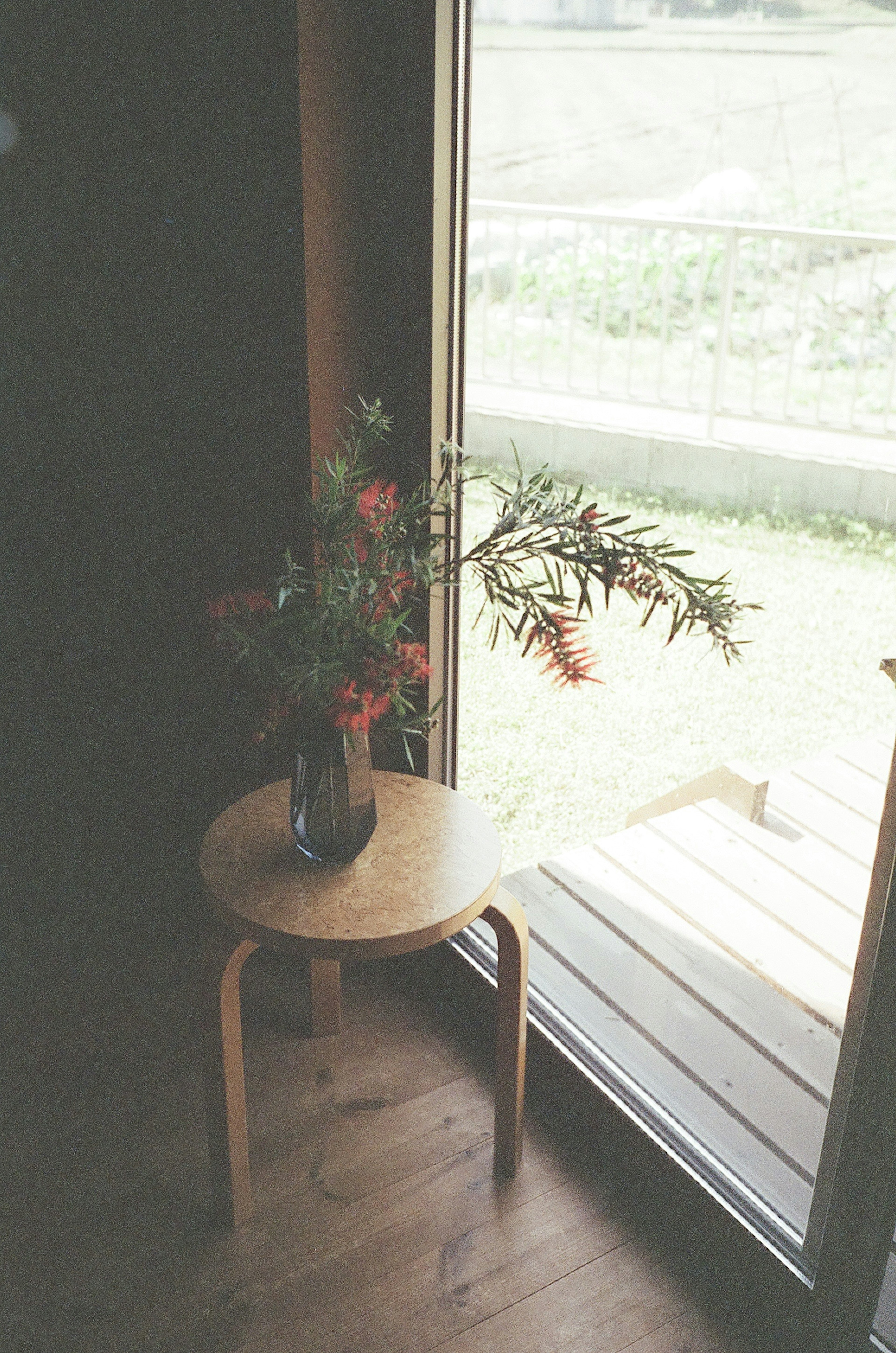 窓際の木製のテーブルに花瓶と花が置かれているシンプルな室内の風景