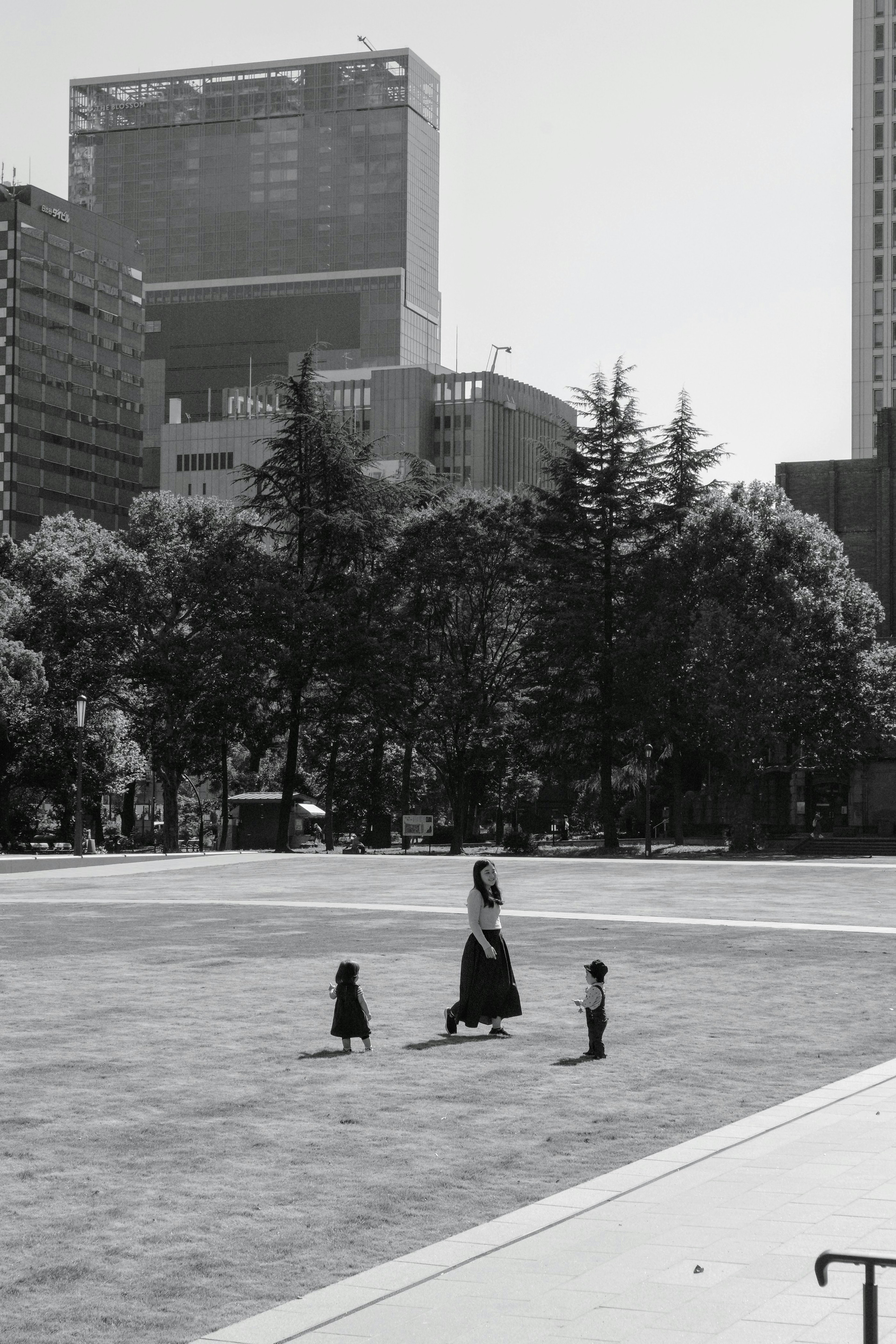 公園で子供たちと一緒に歩く女性のモノクロ写真