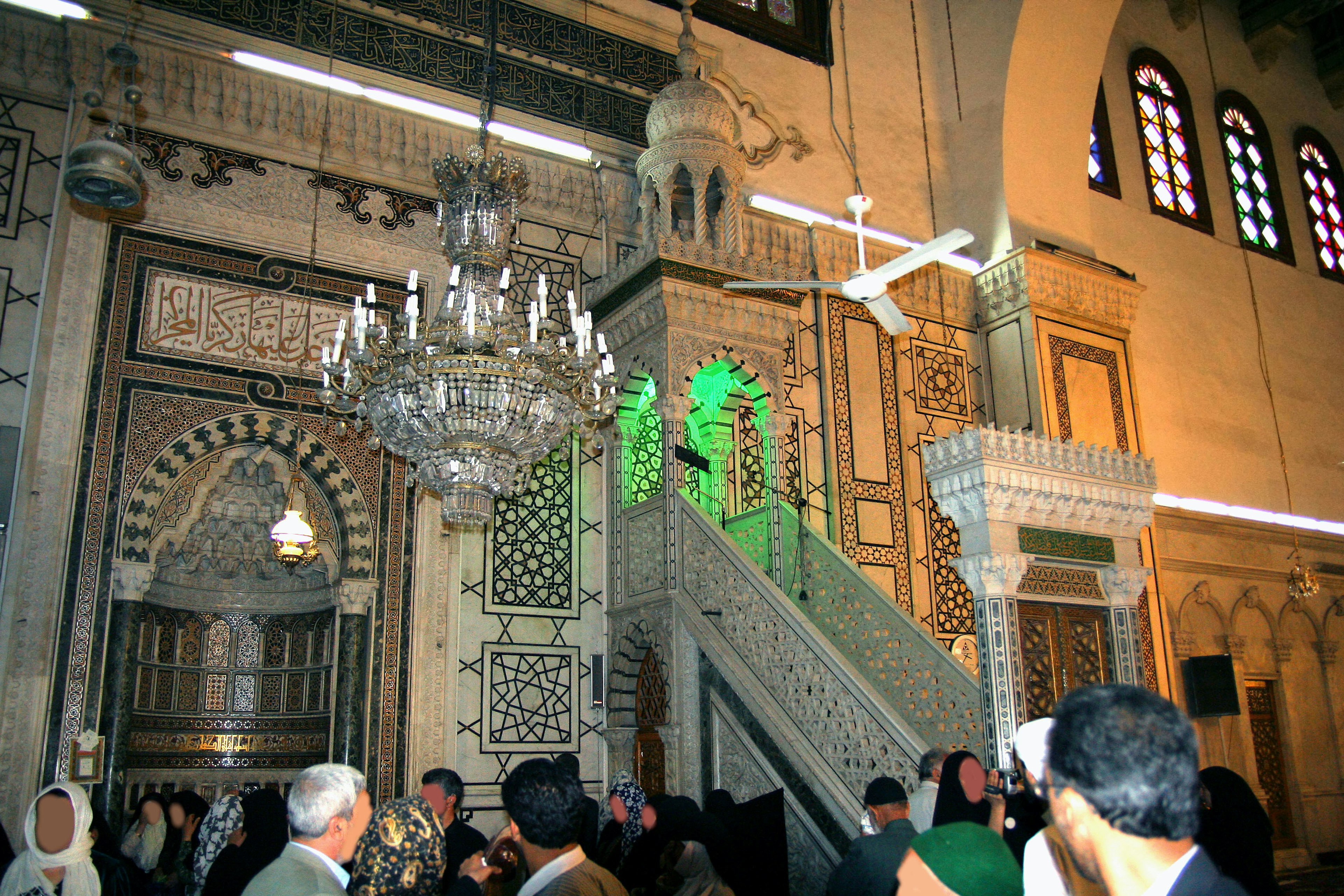 Interior of a mosque with intricate decorations and people gathered