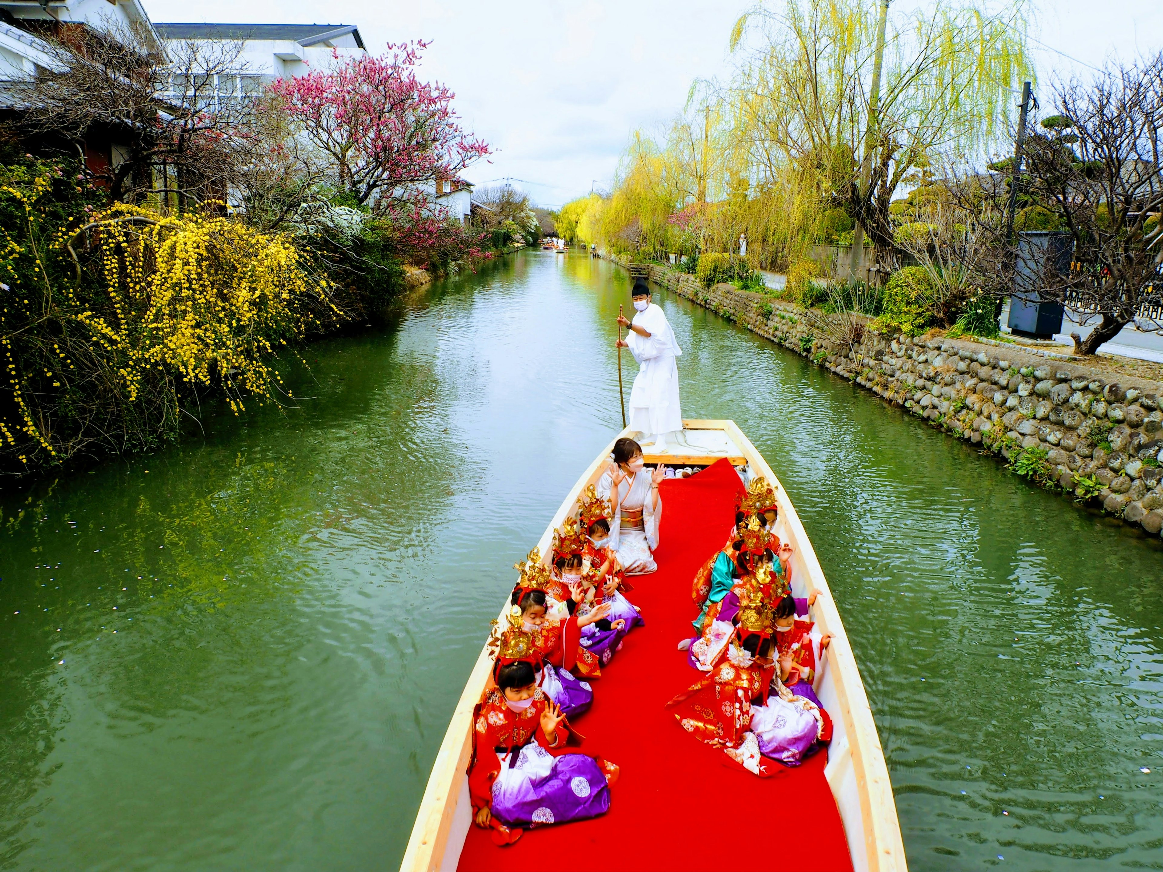 Children sitting on a boat with a woman in white clothing on a river