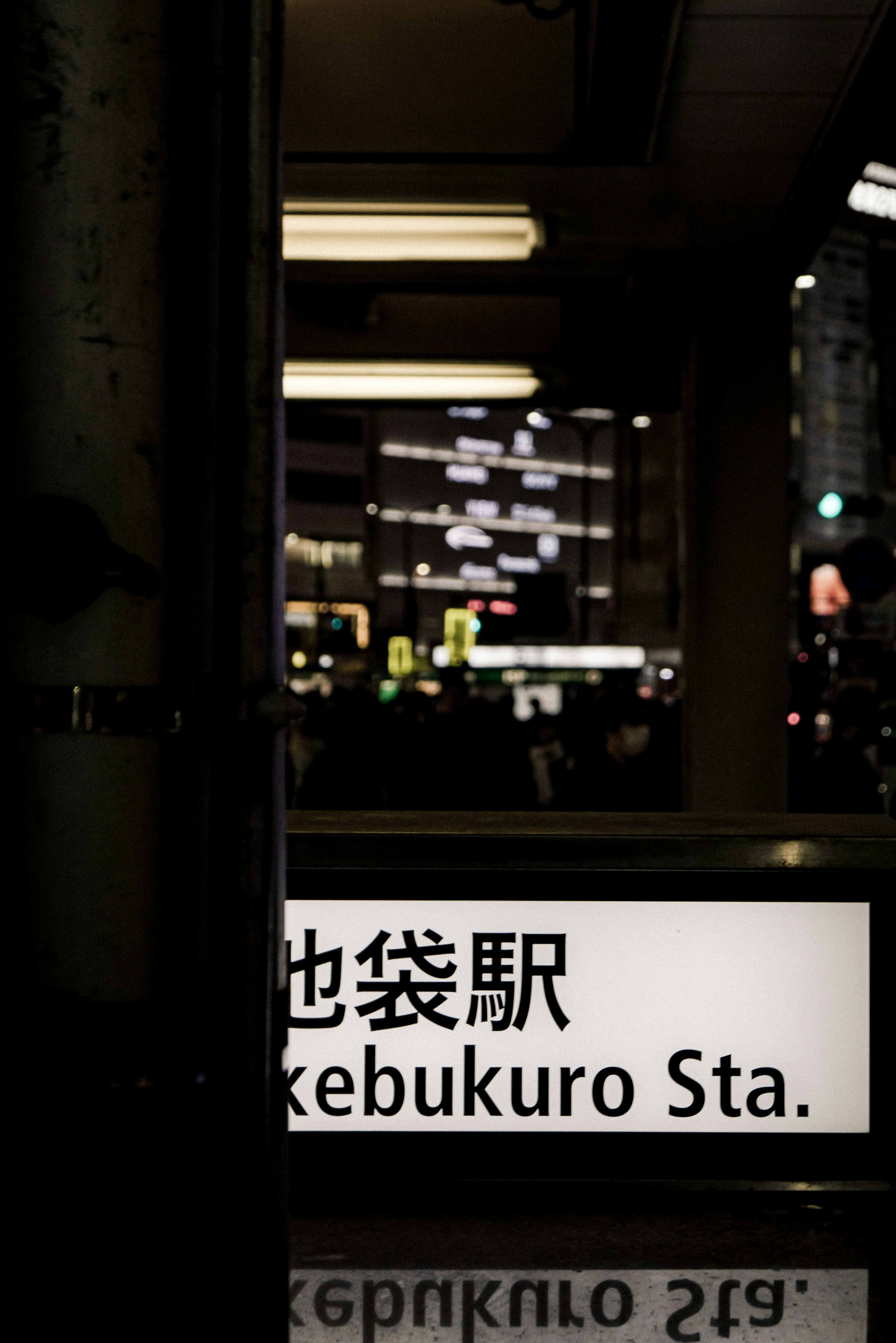 Vista notturna del cartello della stazione Ikebukuro parzialmente visibile