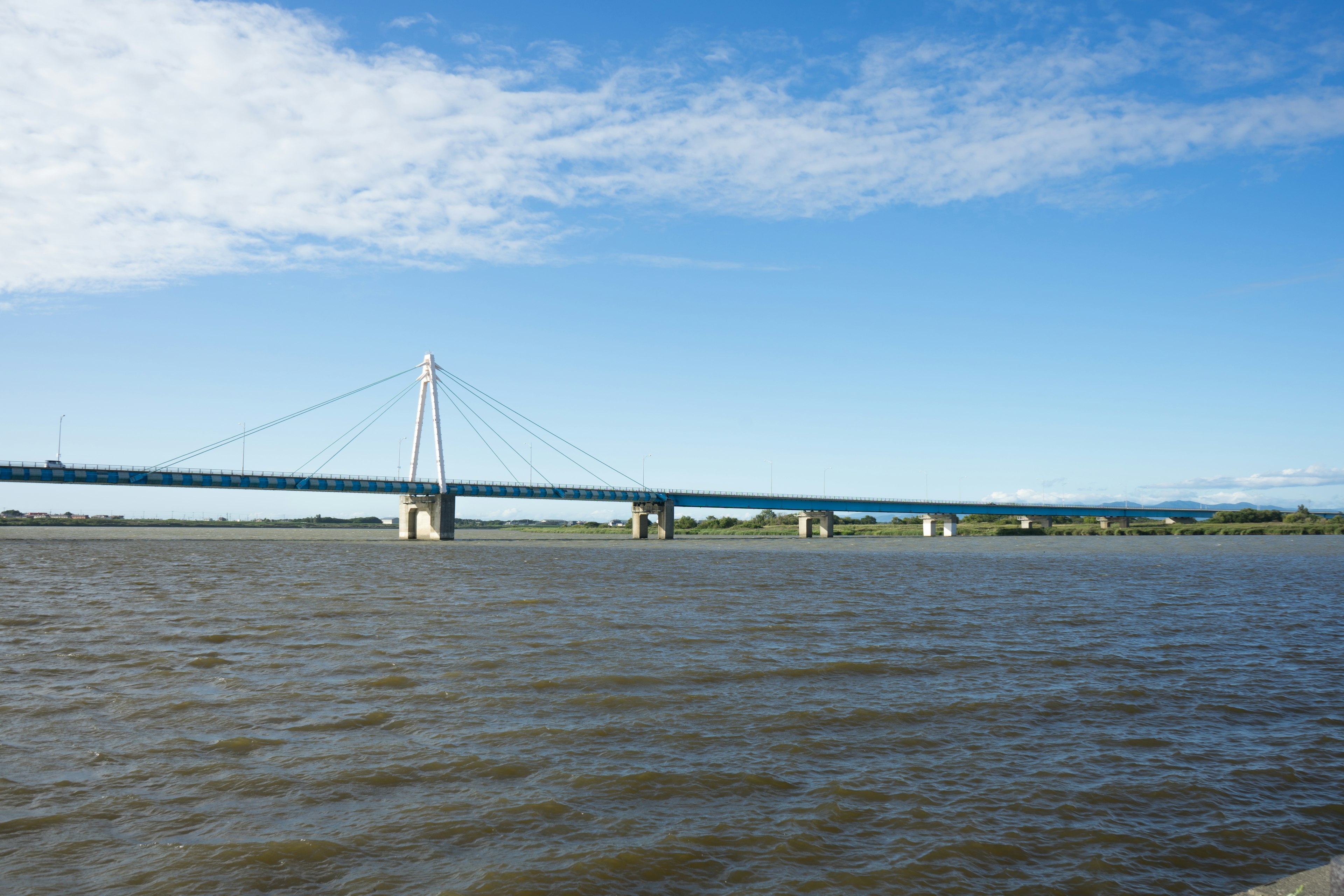 Malersiche Aussicht auf einen Fluss und eine Schrägseilbrücke unter einem blauen Himmel