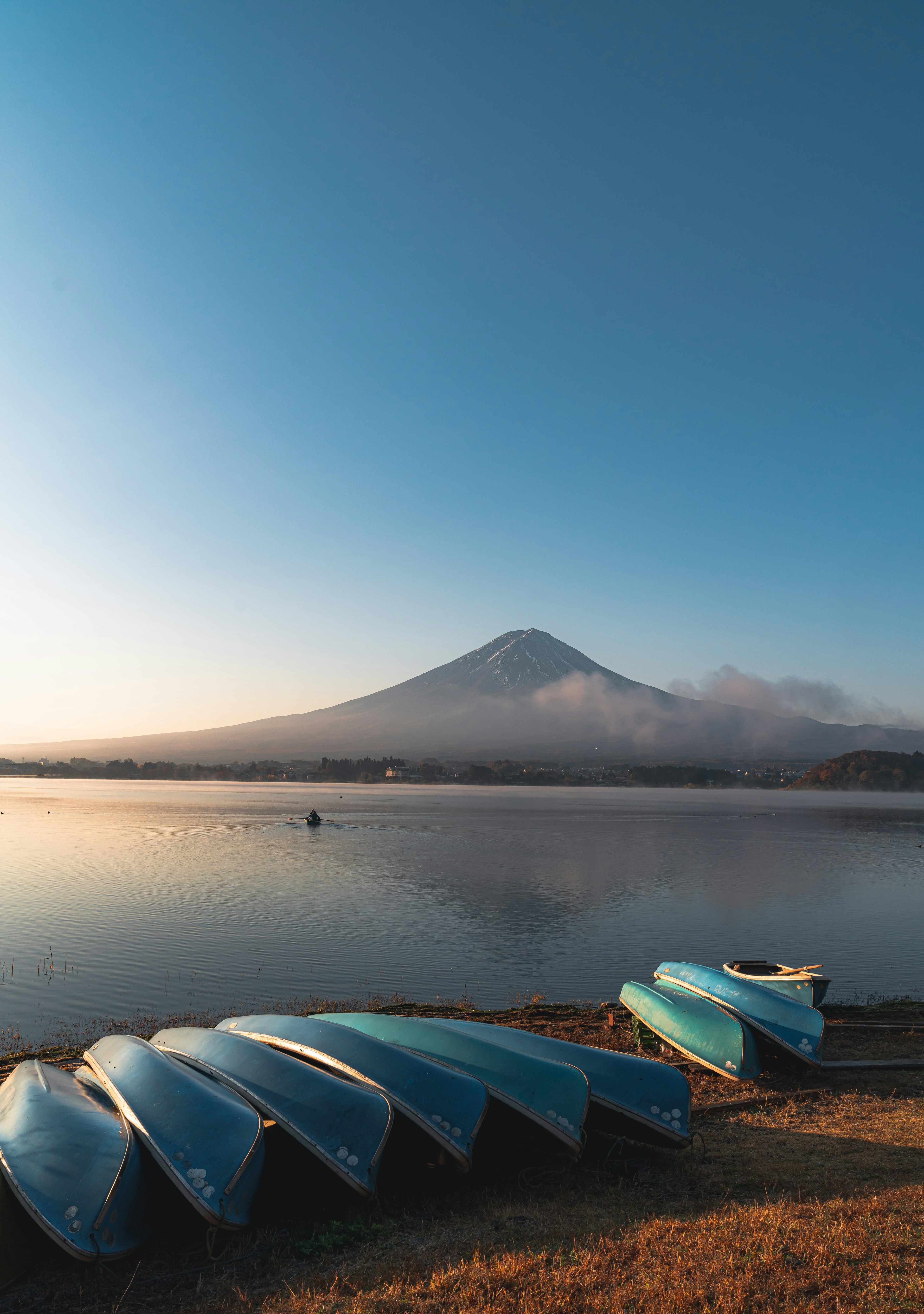 富士山と静かな湖の風景に青いボートが並んでいる