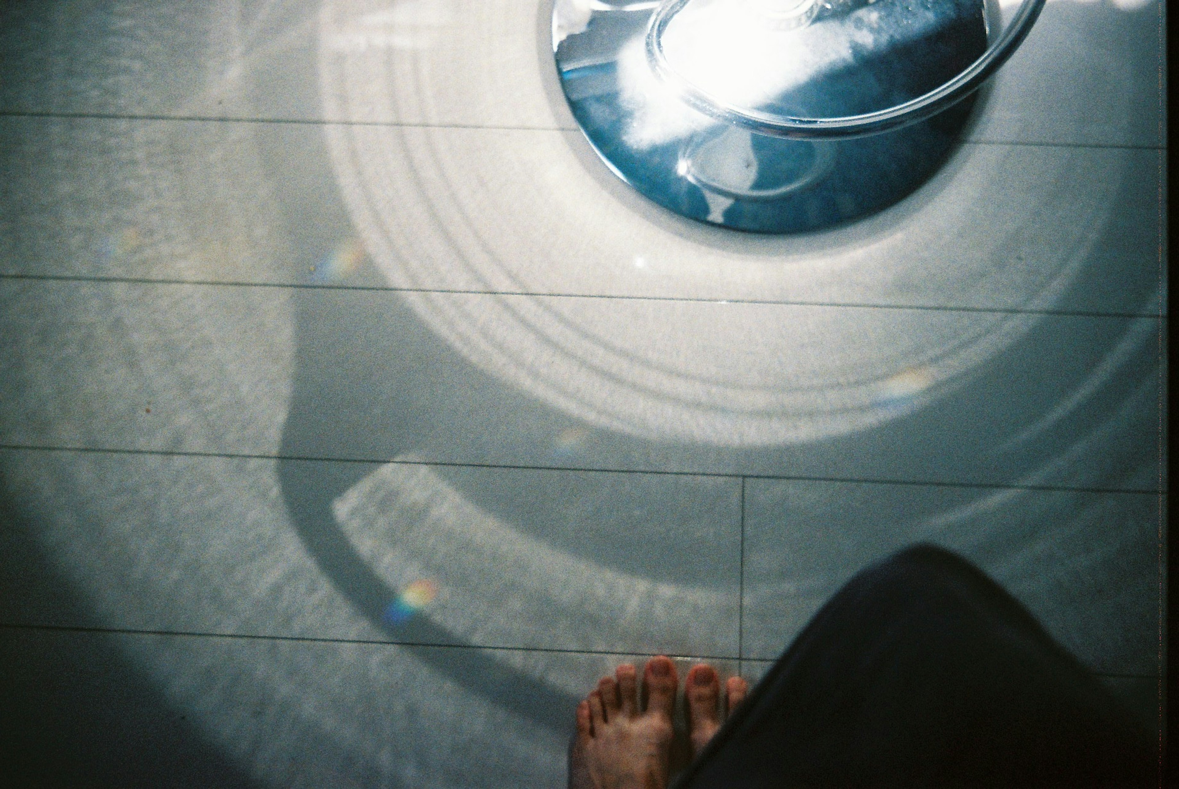 Circular light reflection on the floor with a foot in the frame