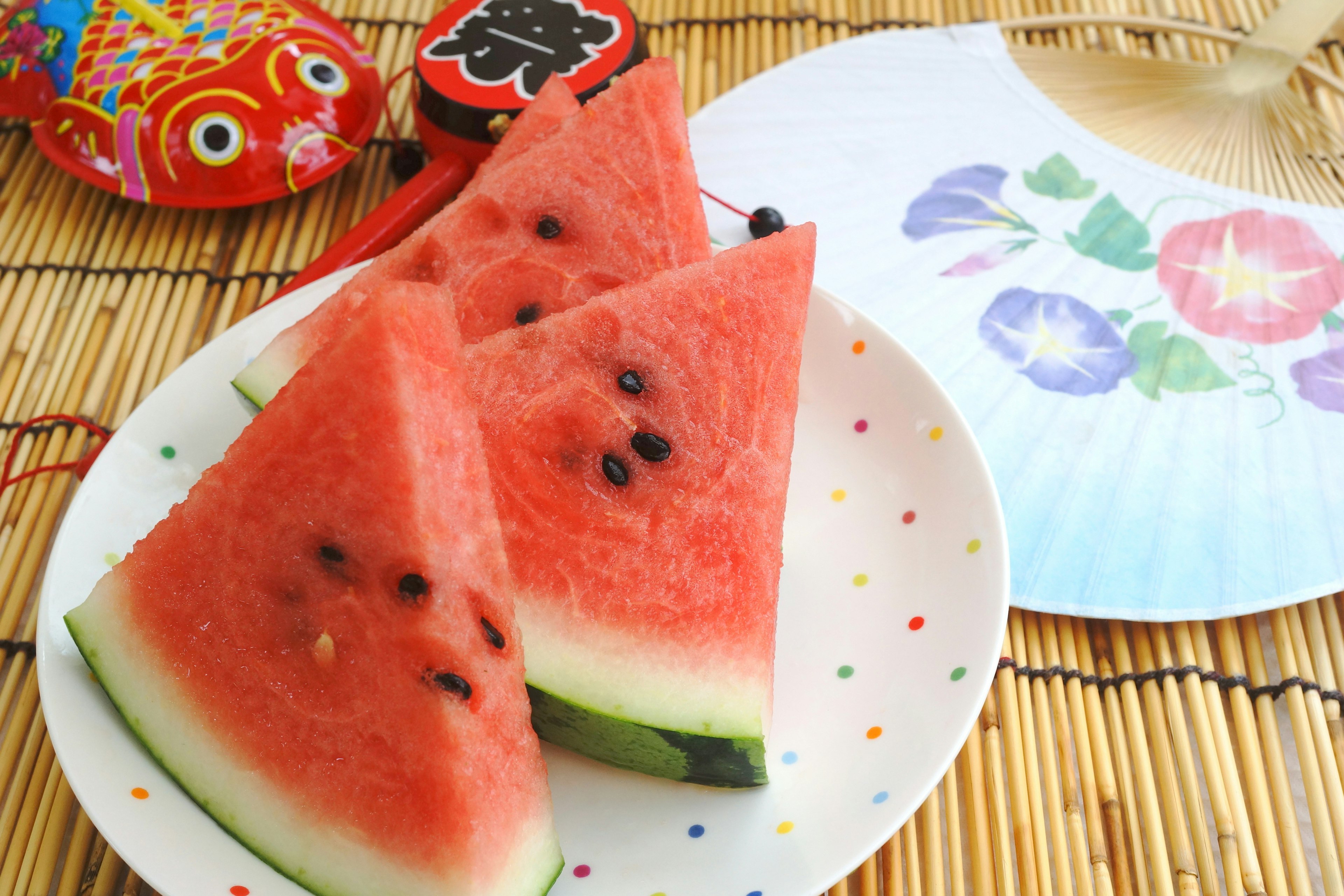 Slices of watermelon on a plate with a decorative fan and an ornament