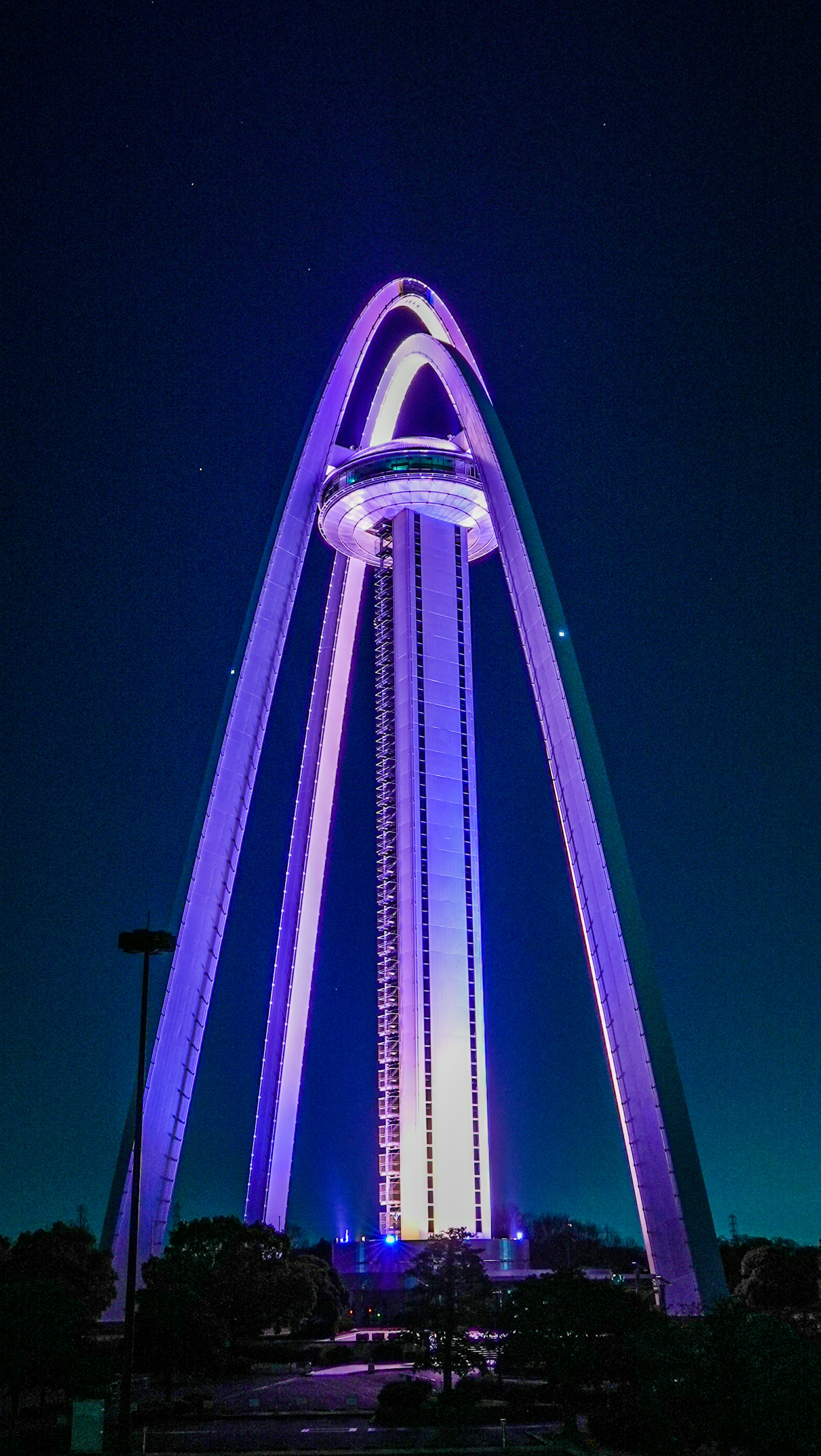 Grande tour en forme d'arc illuminée en lumière violette sur fond de ciel nocturne