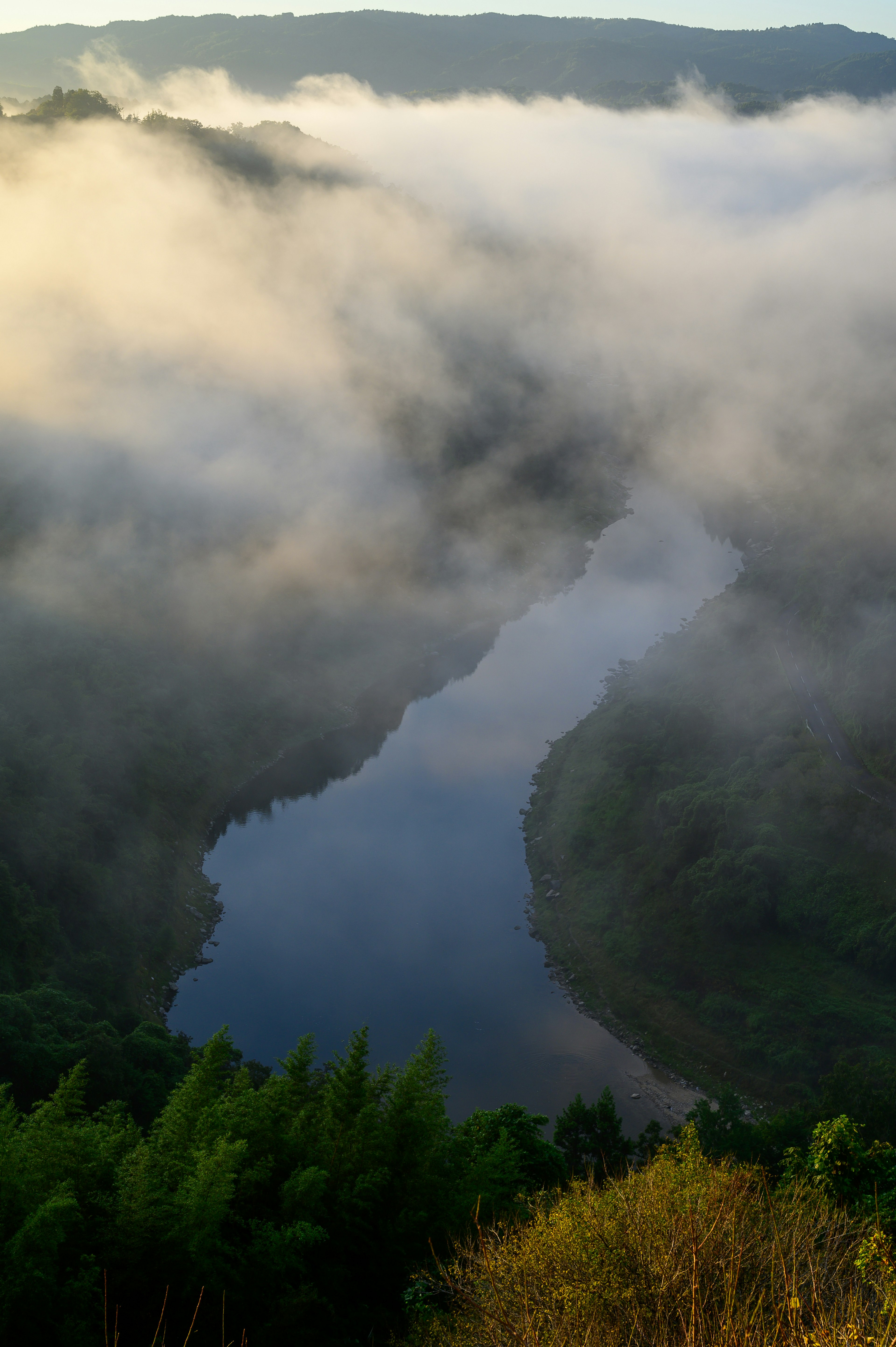 A river winding through misty hills surrounded by lush greenery