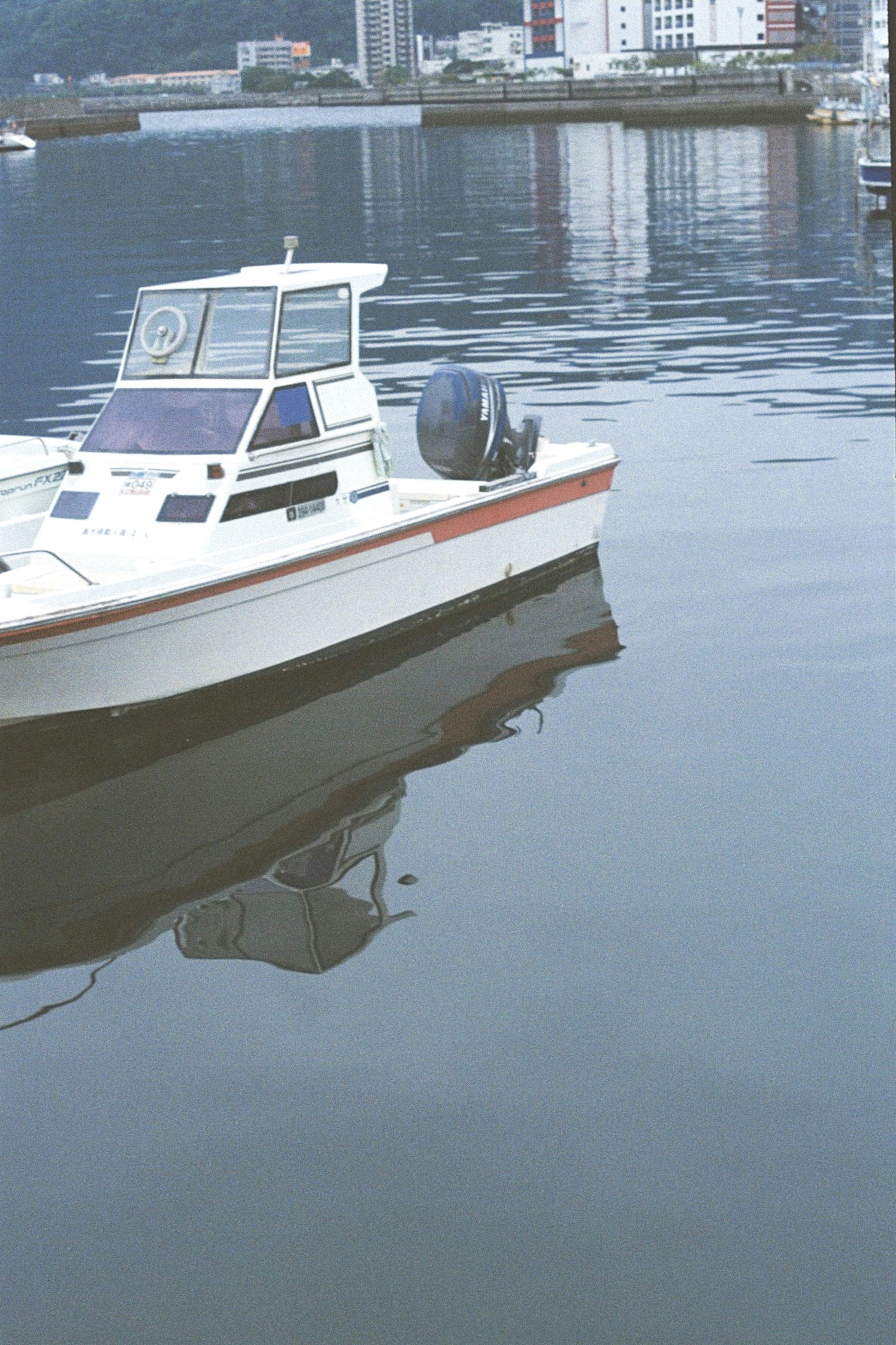 A white boat floating on a calm water surface with its reflection