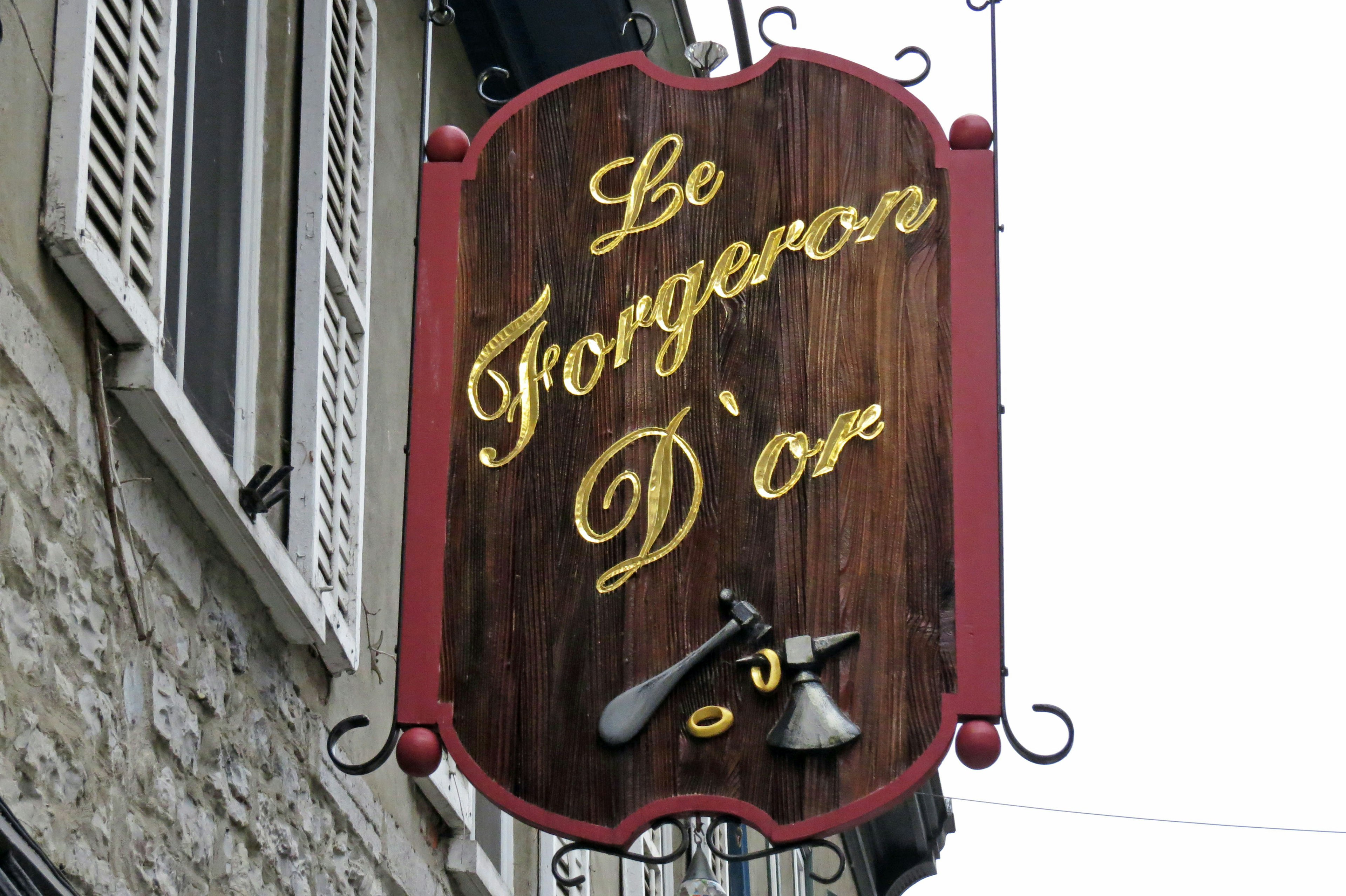 Holzschild mit dem Text 'Le Forgeron D'Or' in goldenen Buchstaben