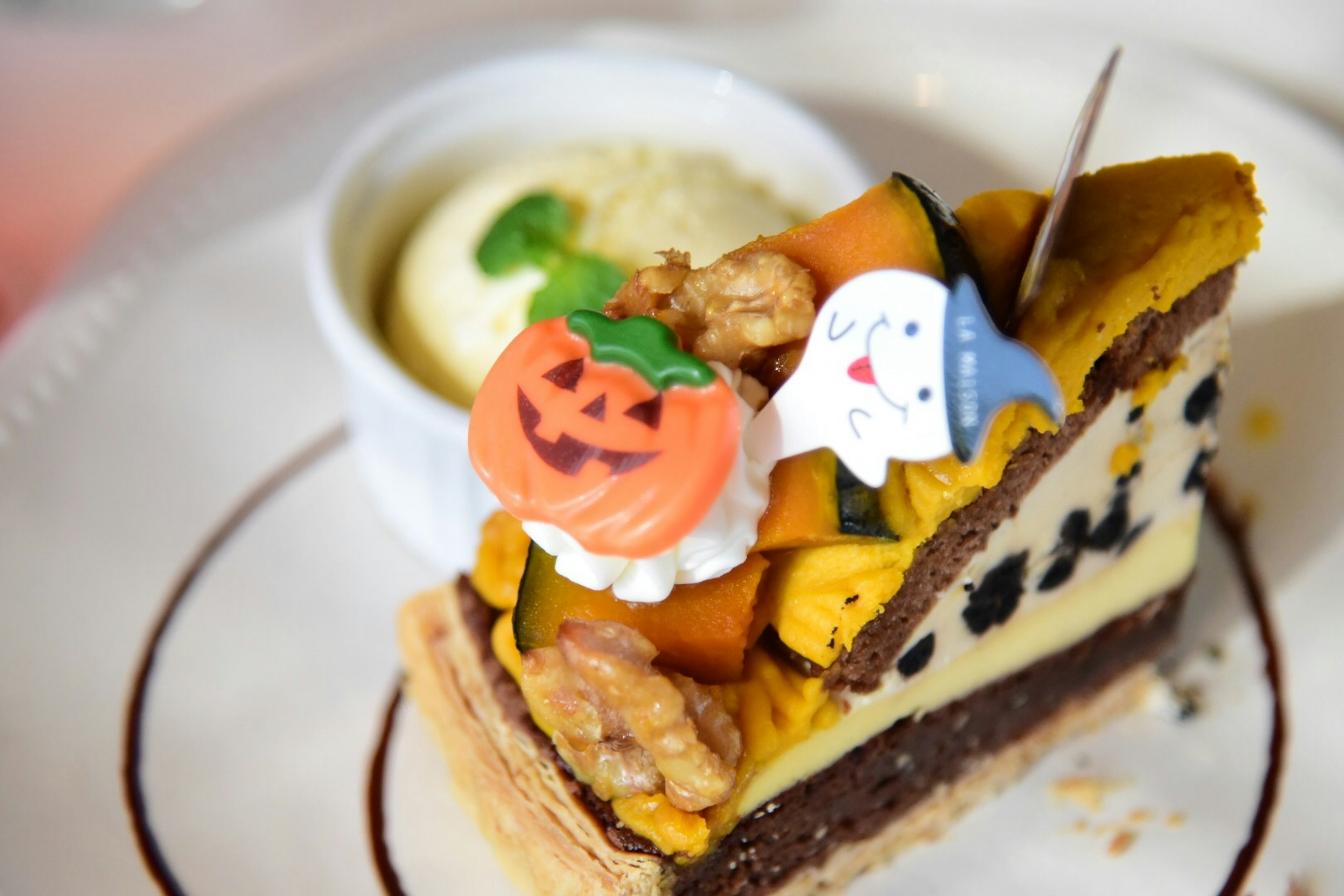 Torta decorata per Halloween con guarnizioni di zucca e fantasma accanto a una pallina di gelato