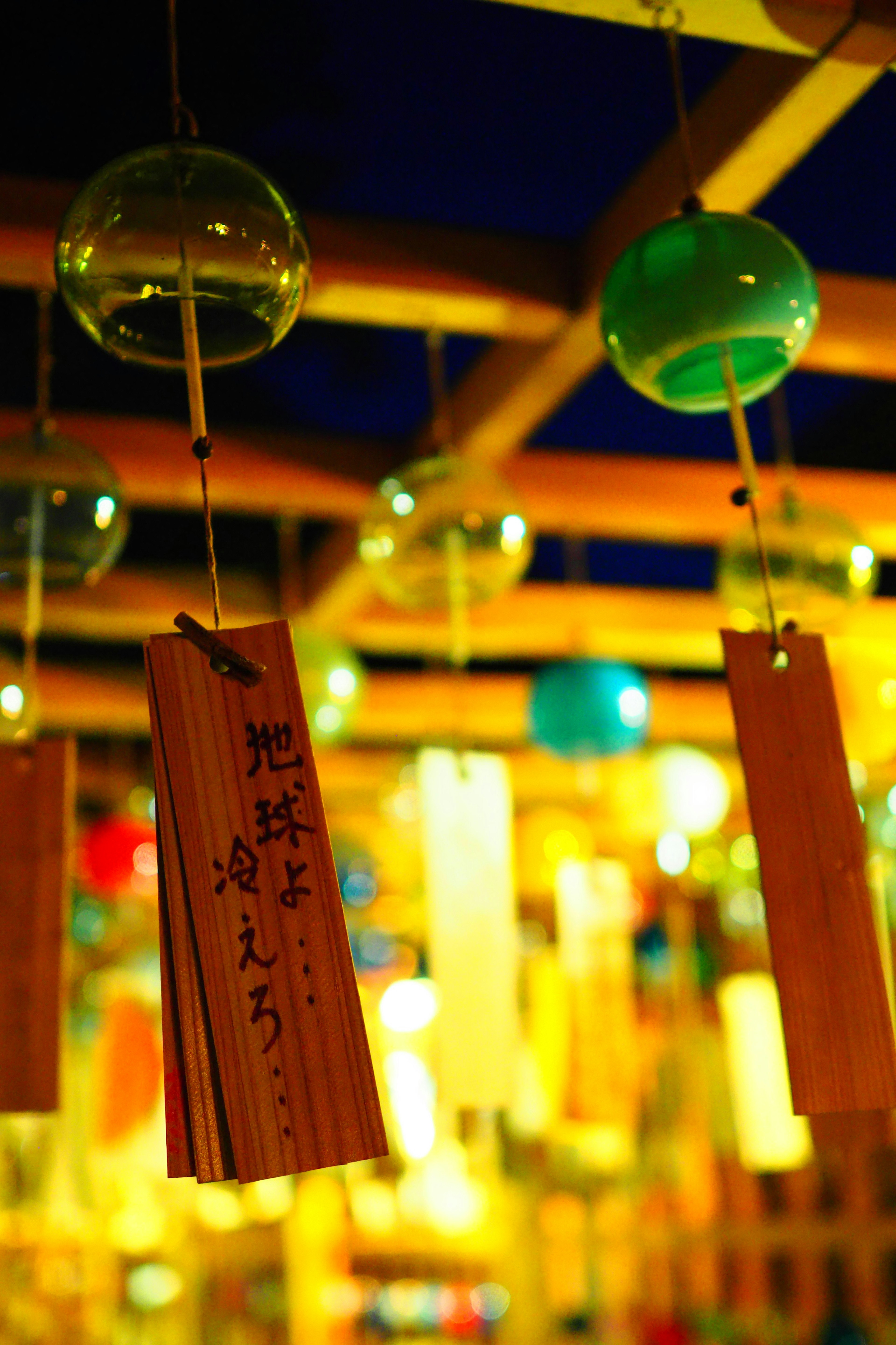 Colorful wind chimes hanging against a bright background with bamboo strips