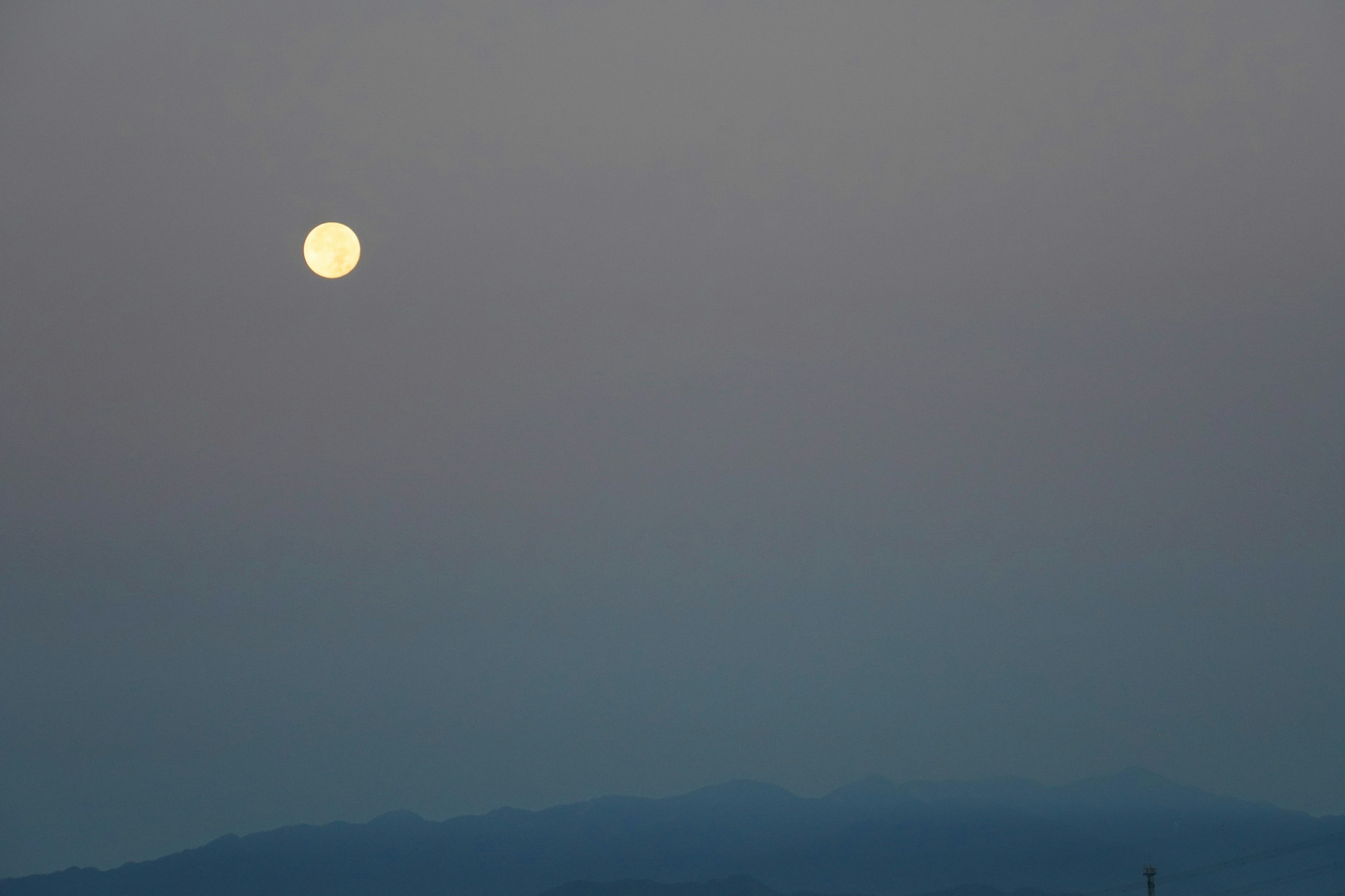 Luna piena in un cielo dim e montagne lontane