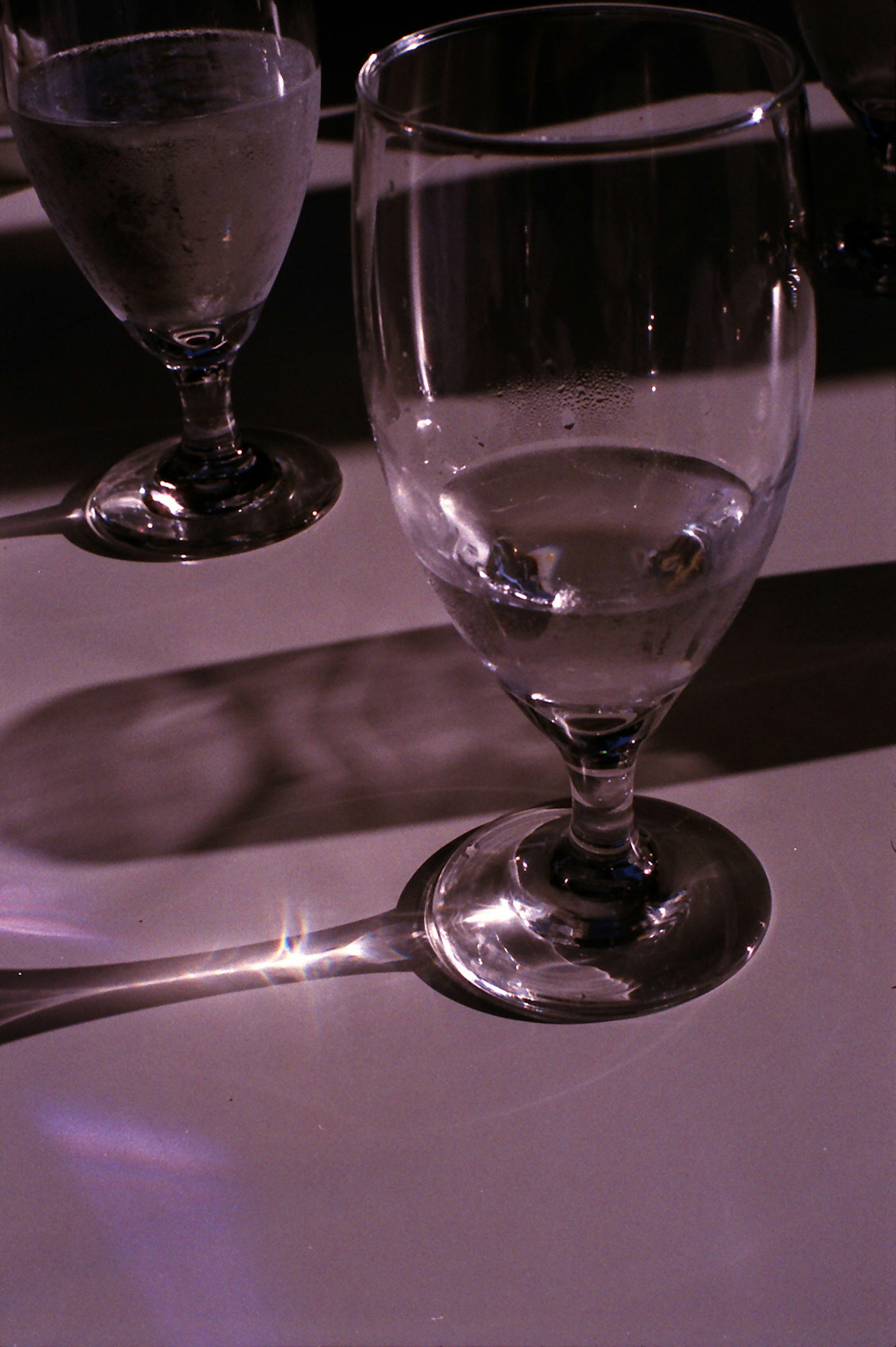 Close-up of transparent glasses and a spoon with beautiful light reflections