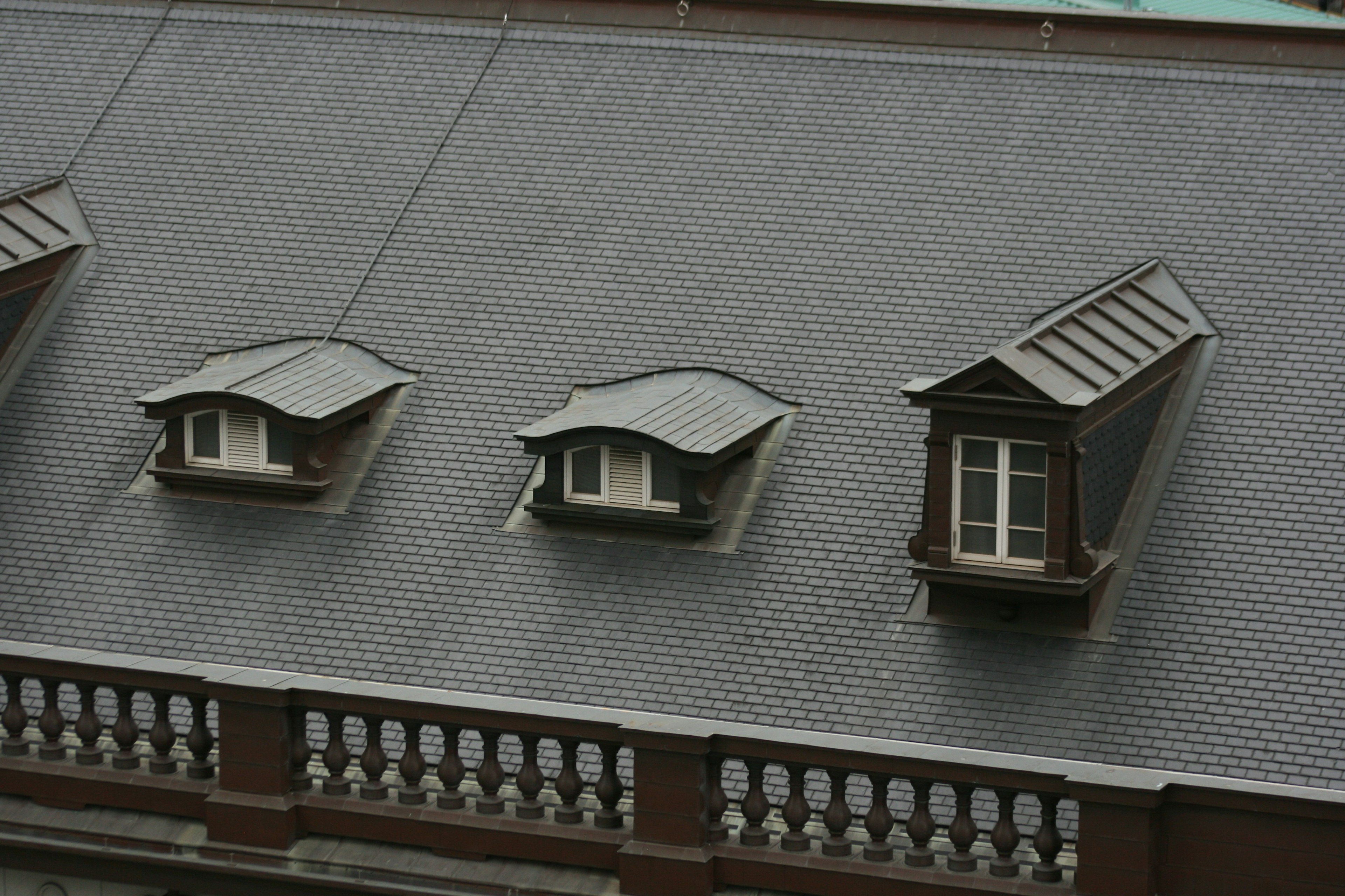 Trois petites fenêtres sur un toit en pente avec un design architectural unique