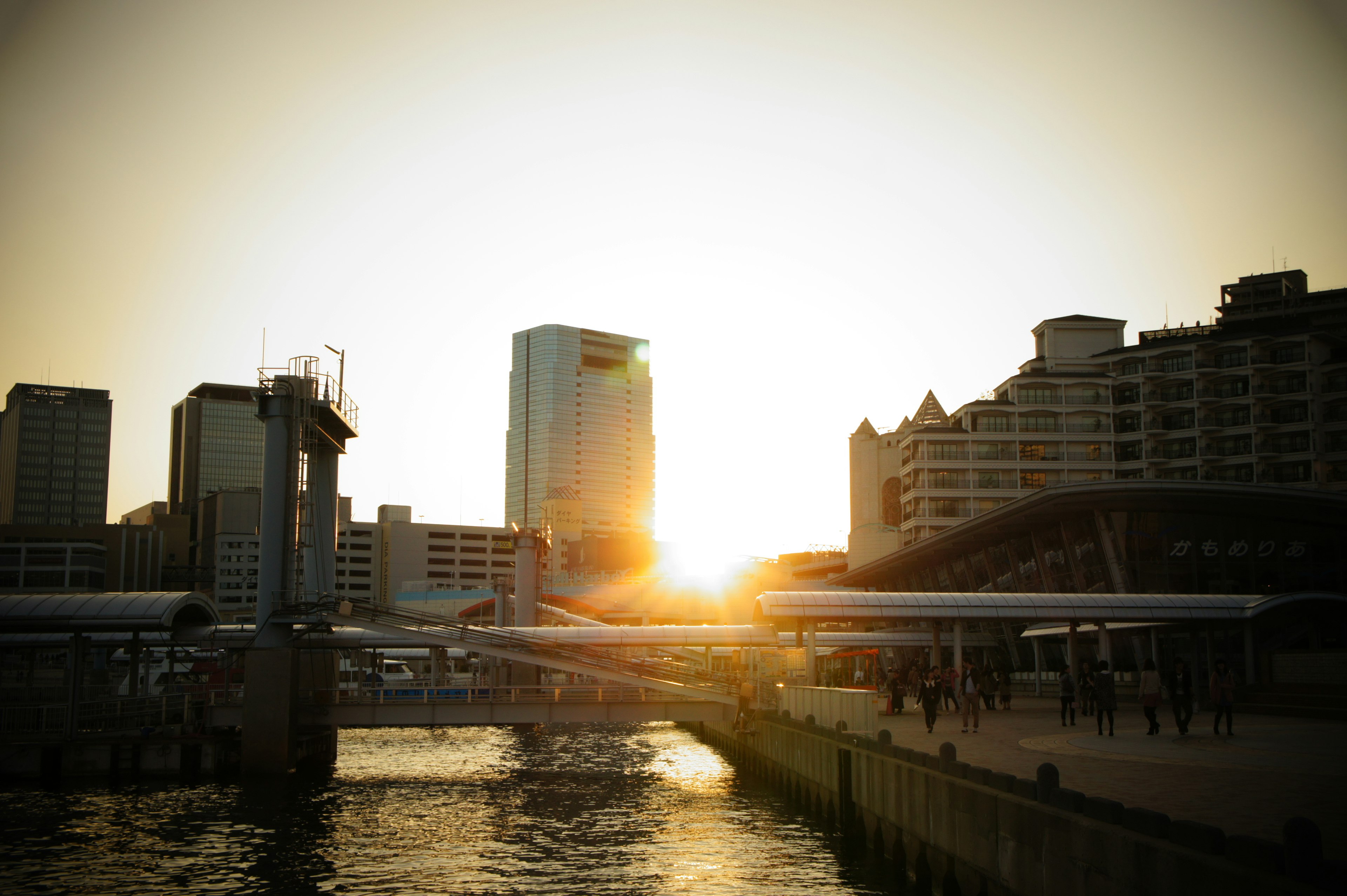 Urban landscape with sunset over the river featuring skyscrapers and people