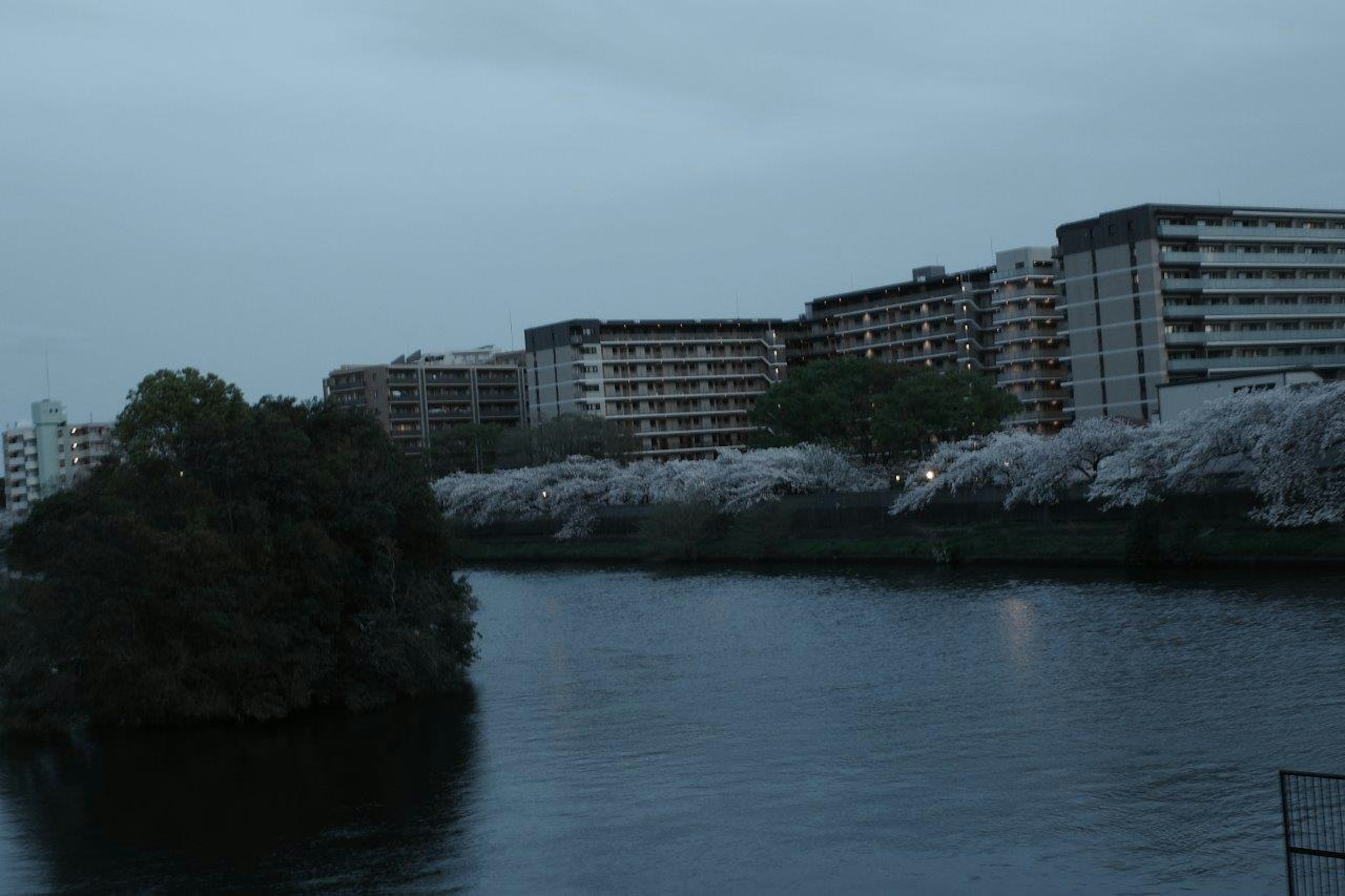 Calm river with surrounding buildings under evening twilight