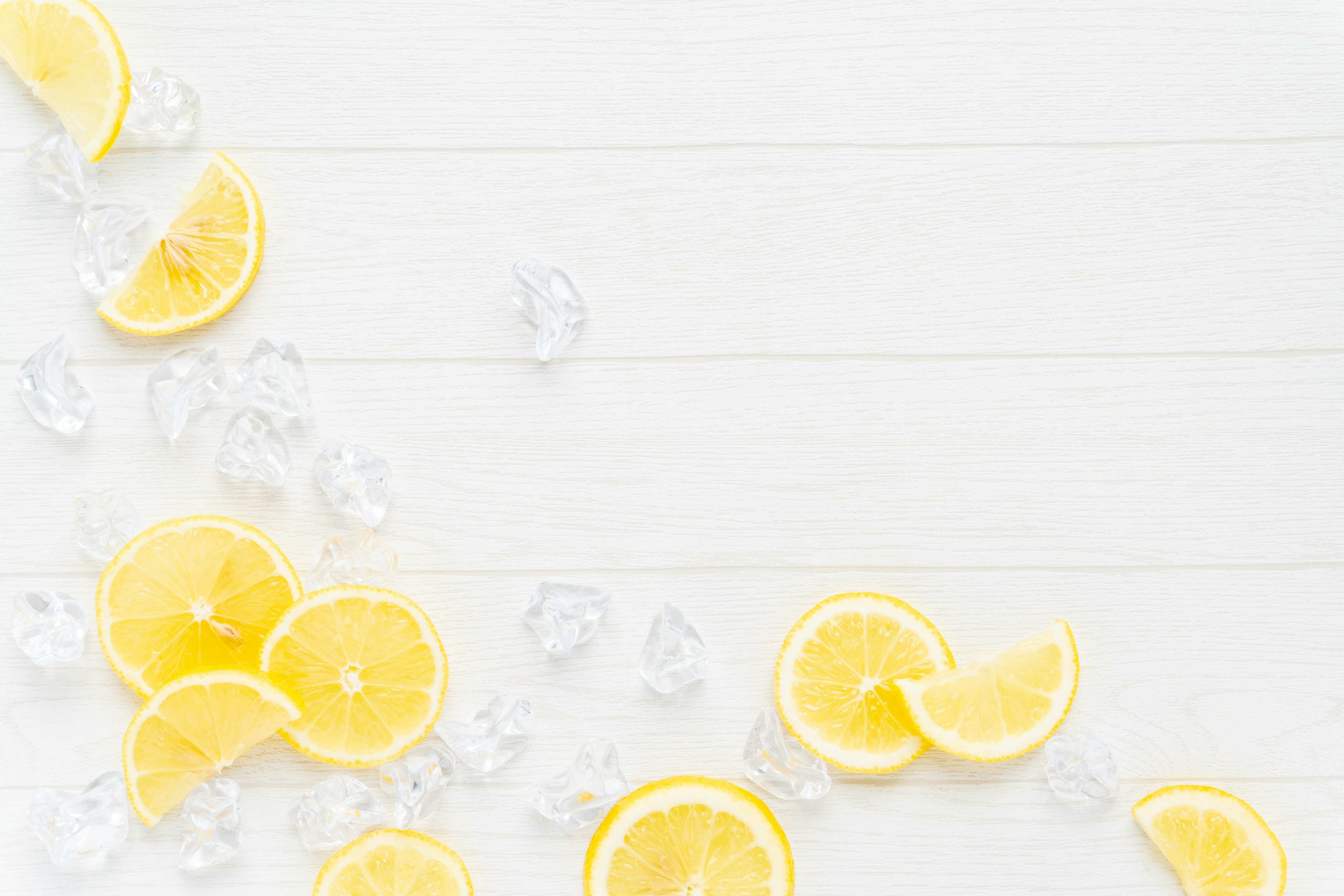 Sliced lemons and ice cubes scattered on a white background