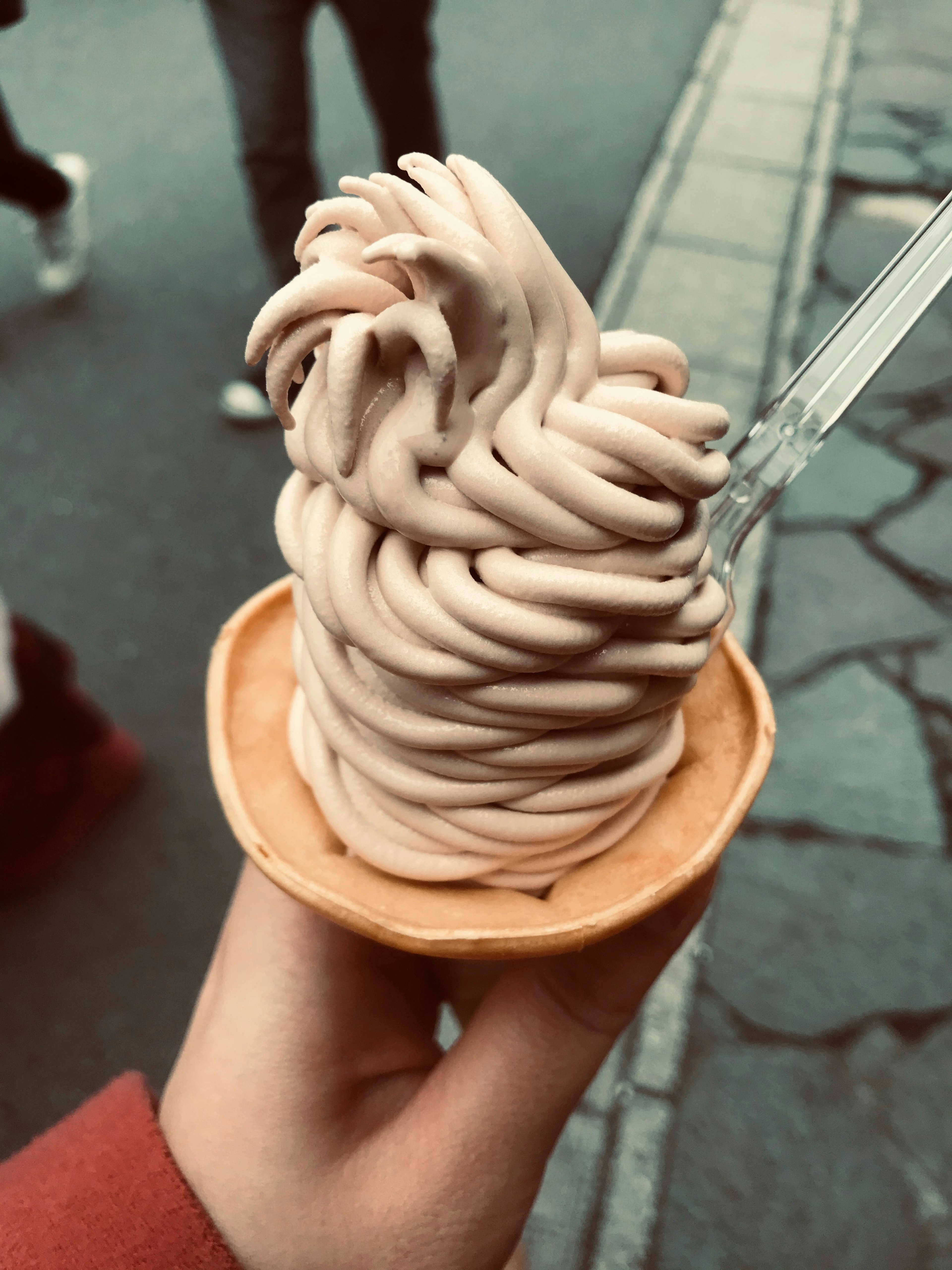 A hand holding a swirl of Mont Blanc ice cream in a cone