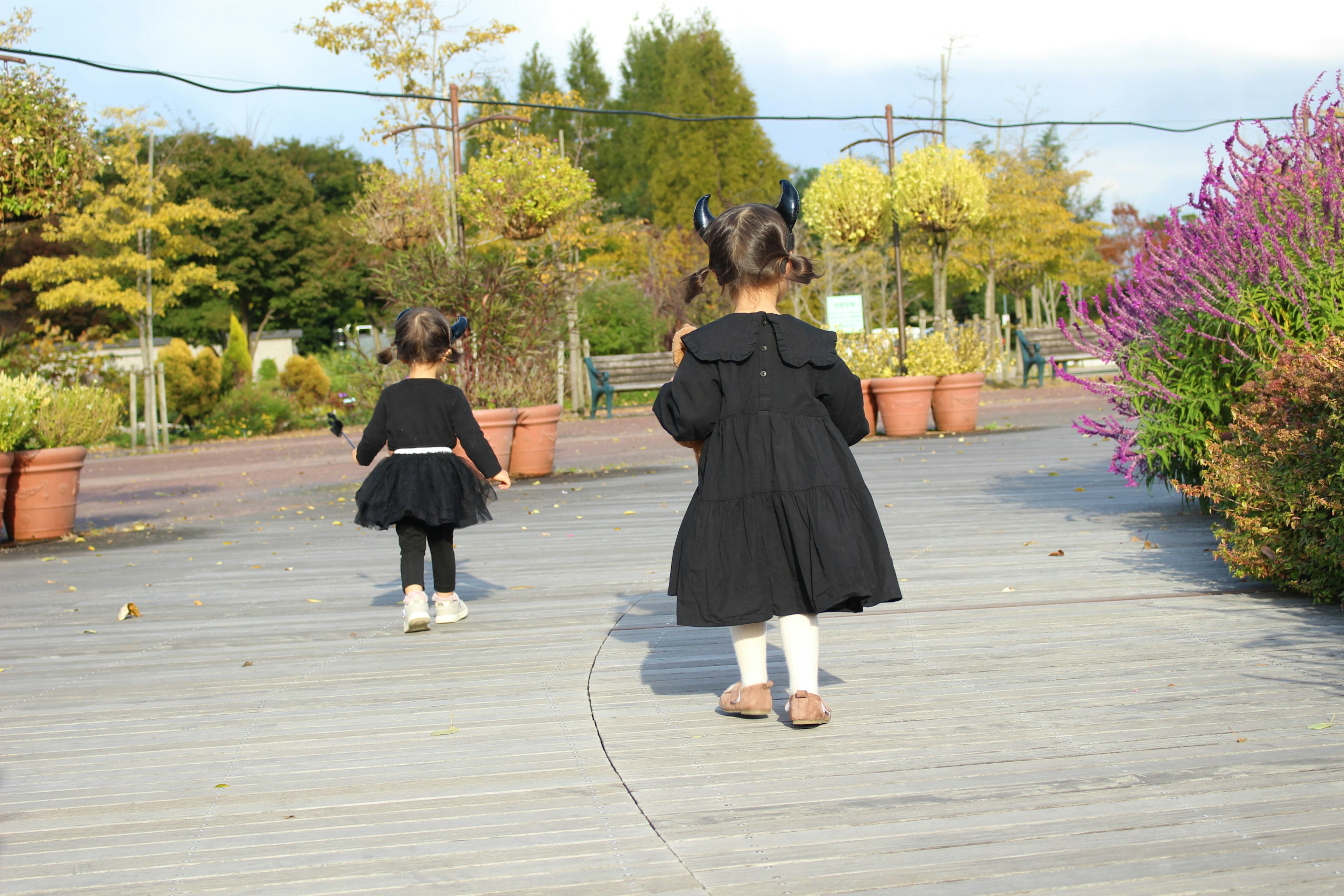 二人の子供が黒いドレスを着て公園を歩いている